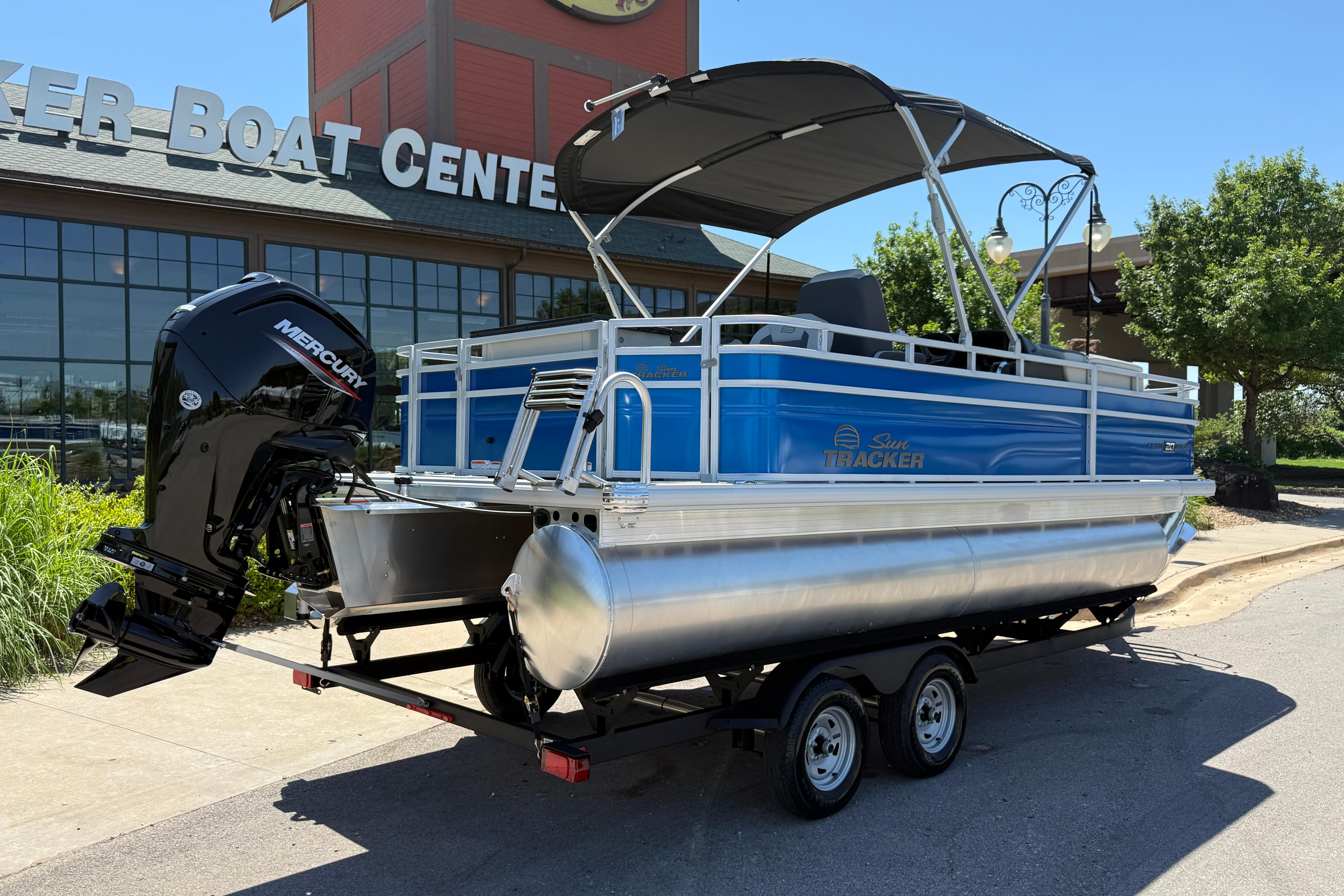 2026 Sun Tracker Fishin' Barge 20 DLX pontoon boat on trailer outside dealership.