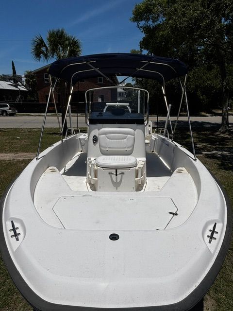 A 2008 Boston Whaler 200 Dauntless with a blue sunshade, parked on a grassy area.