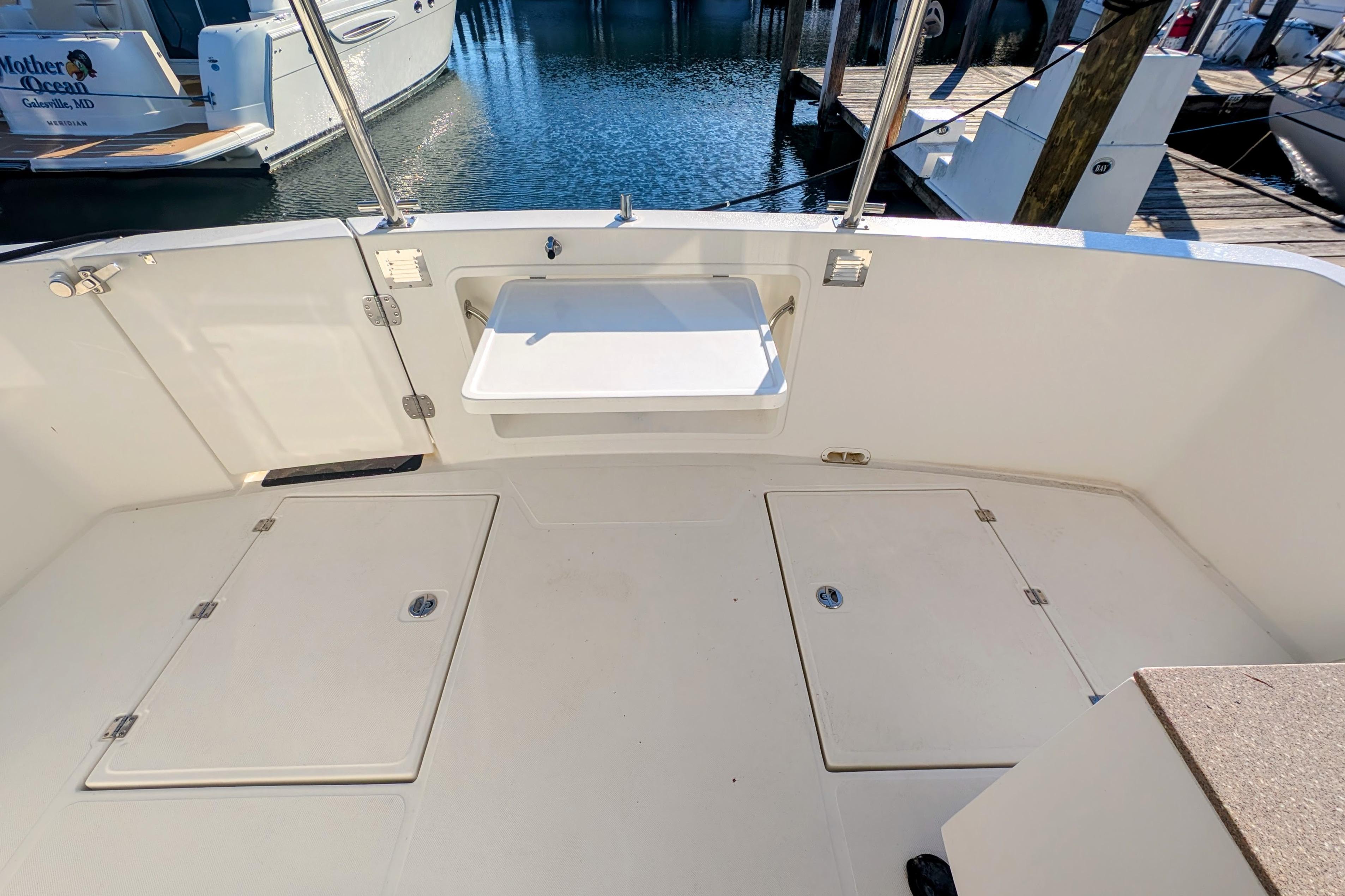 2015 American Tug 435 boat deck with storage hatches and a foldable table, docked at marina.