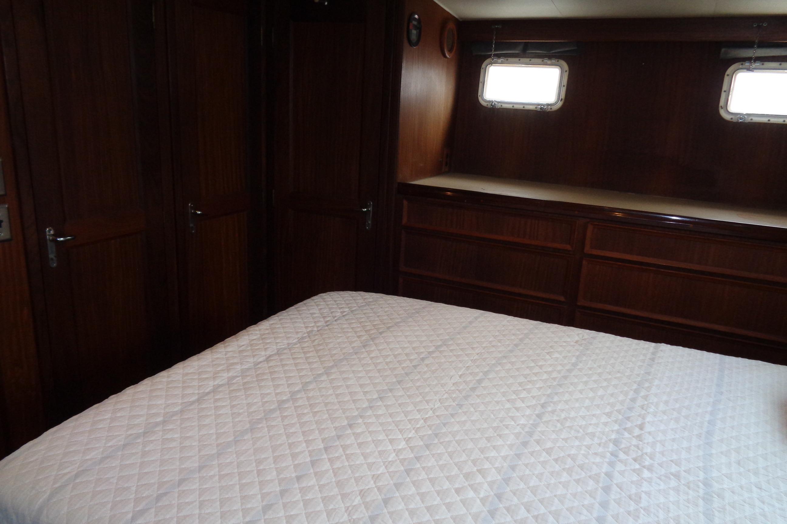 Interior cabin of 1981 Hatteras 48 Cockpit Motor Yacht with wood paneling and bed.