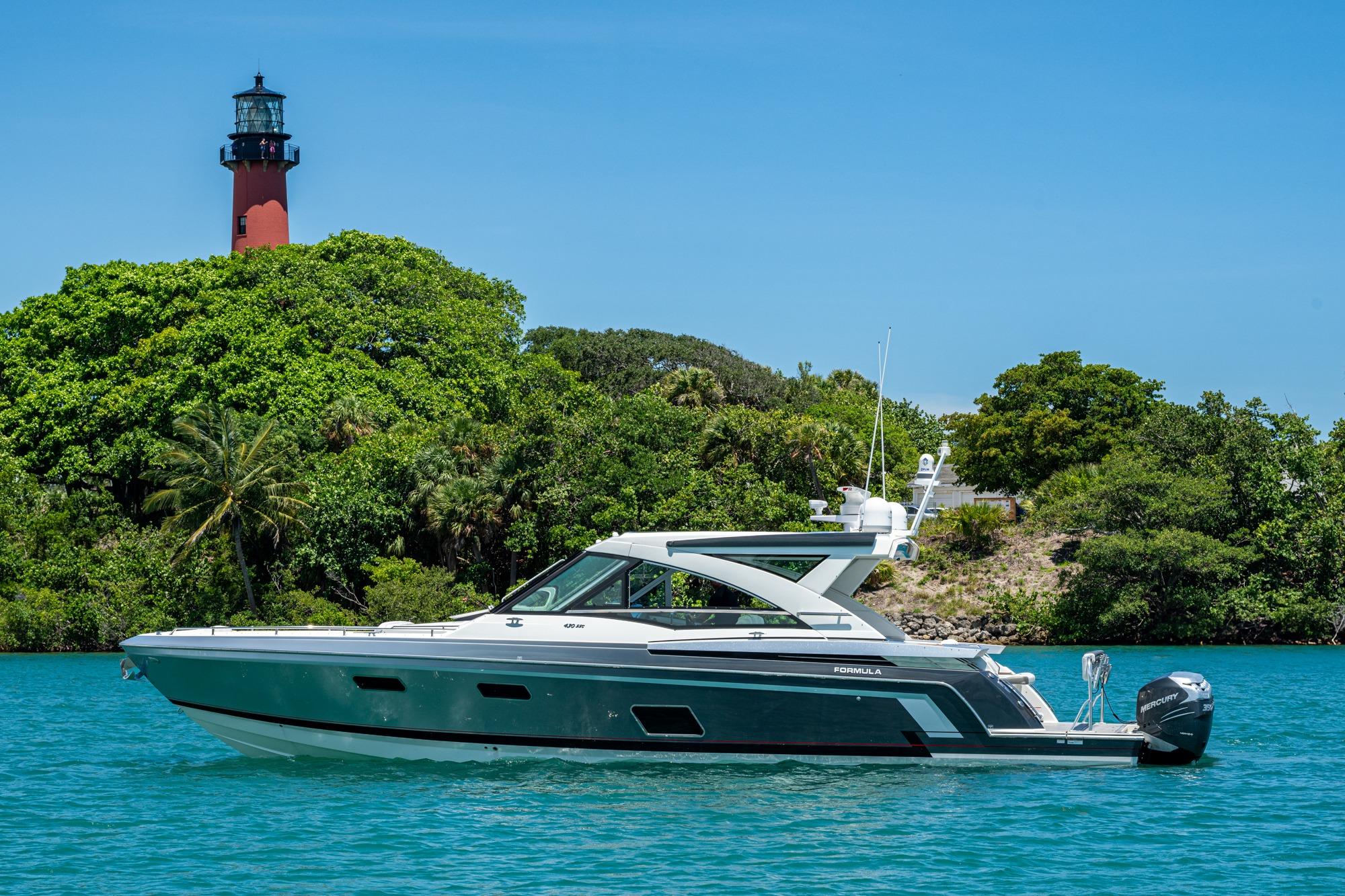 2019 Formula 430 Super Sport Crossover yacht near lush island with lighthouse.