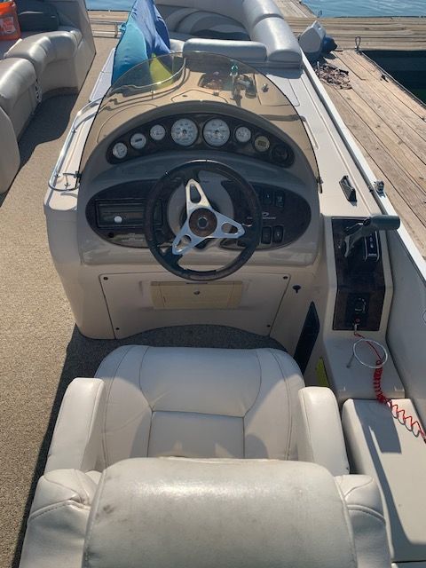 The image shows a boat's cockpit with a steering wheel and instruments.