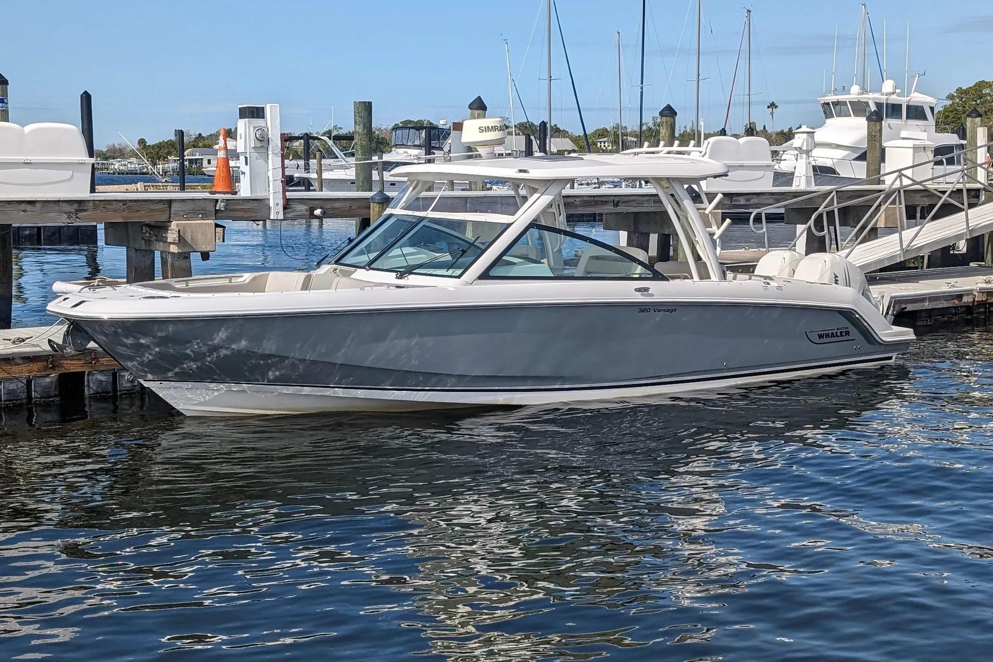 2017 Boston Whaler 320 Vantage boat docked at marina, calm water reflections.