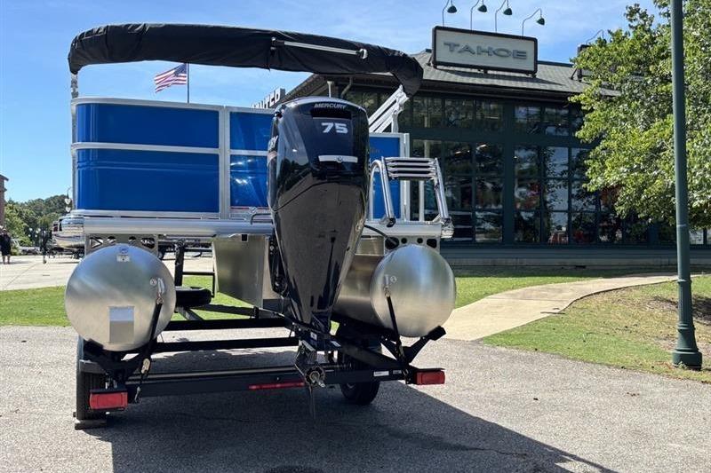 2026 Sun Tracker Party Barge 18 DLX on trailer, parked near a building.