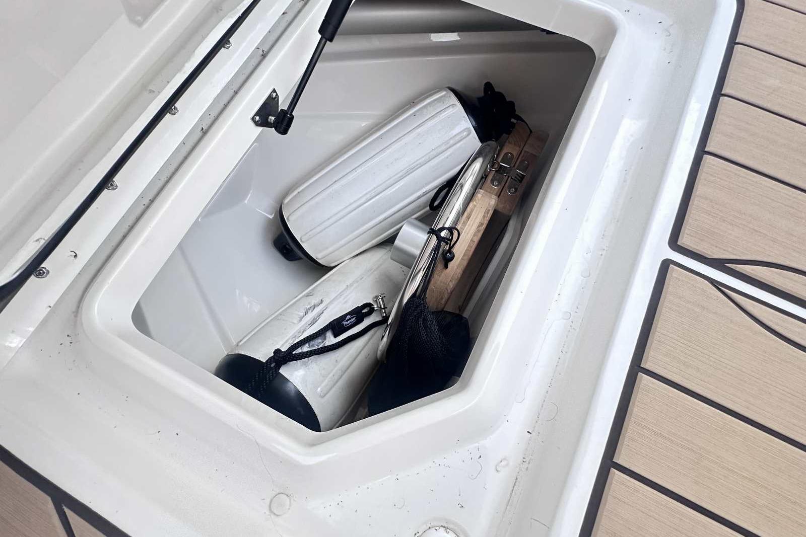 Storage compartment on 2024 Sea Ray SLX 400 boat with fenders and equipment.