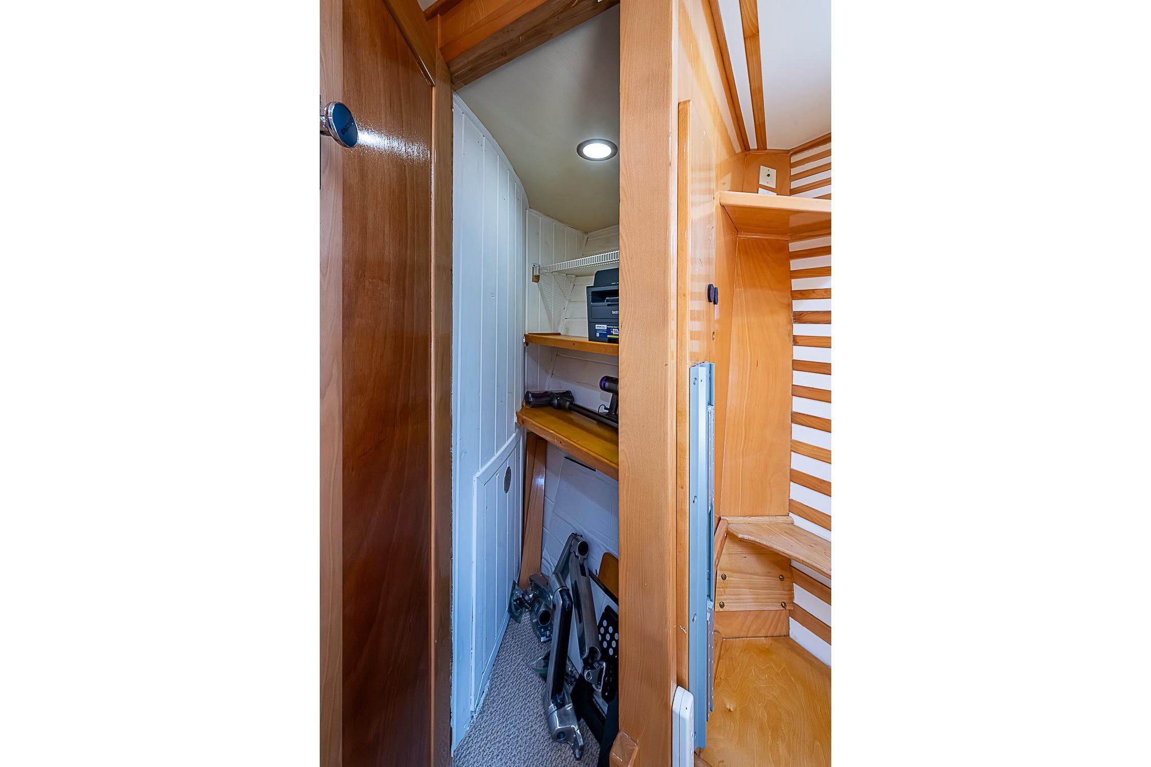 Interior of a boat with wooden shelves and a door to a small room.