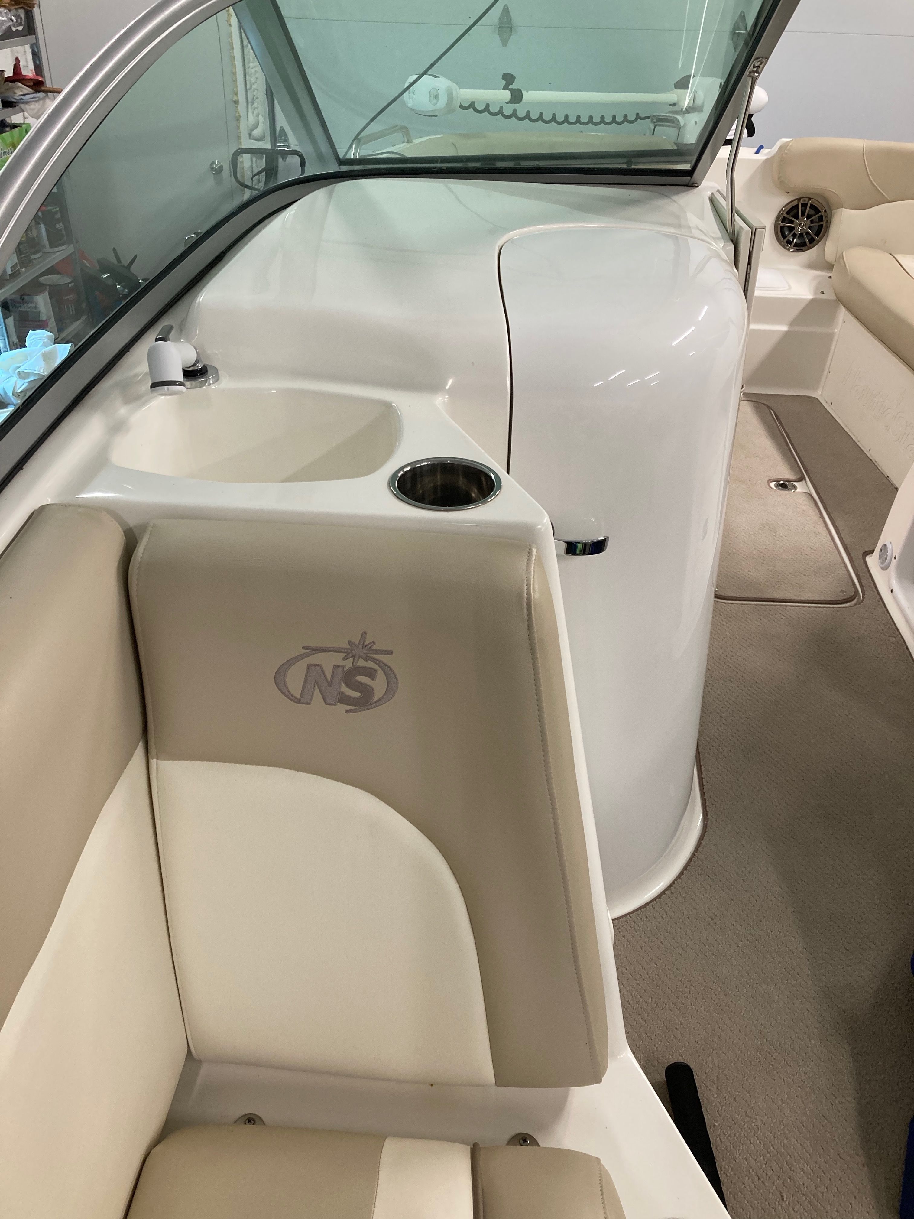Interior view of a 2016 Custom 223 DC boat with beige seats and a cup holder.