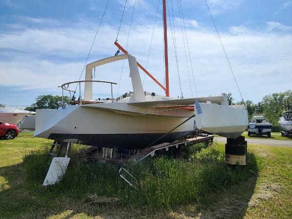 1985 Crowther Buccaneer sailboat on land, grassy area, clear sky background.