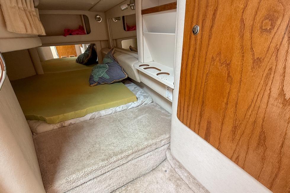 1999 Sea Ray 290 Sundancer cabin interior with bed, shelves, and wooden paneling.