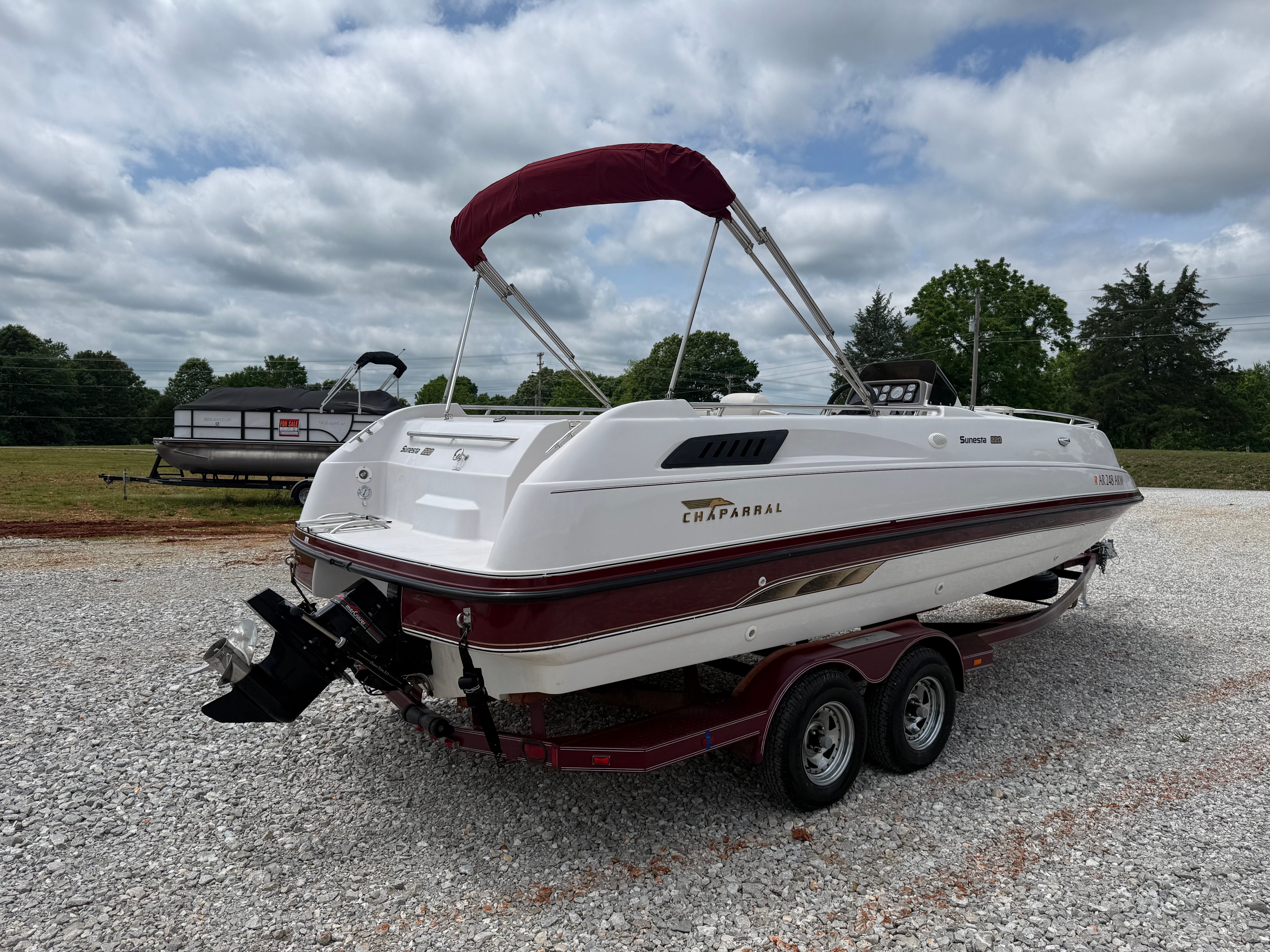 A 1994 Chaparral Sunesta 220 boat on a trailer in a gravel lot.