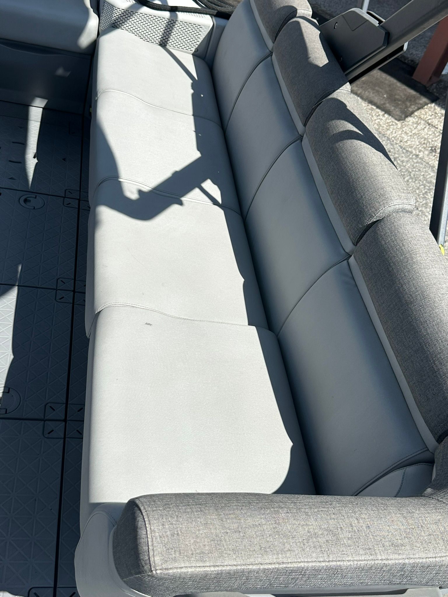 Gray seating bench on a boat with textured flooring.