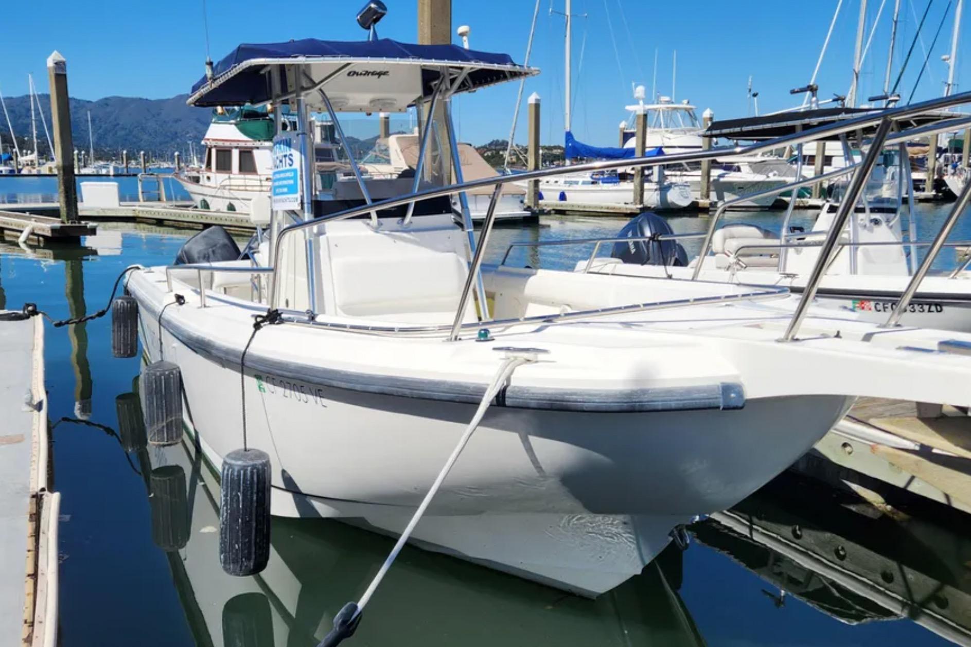 2001 Boston Whaler 26 Outrage boat docked in a marina under clear blue skies.