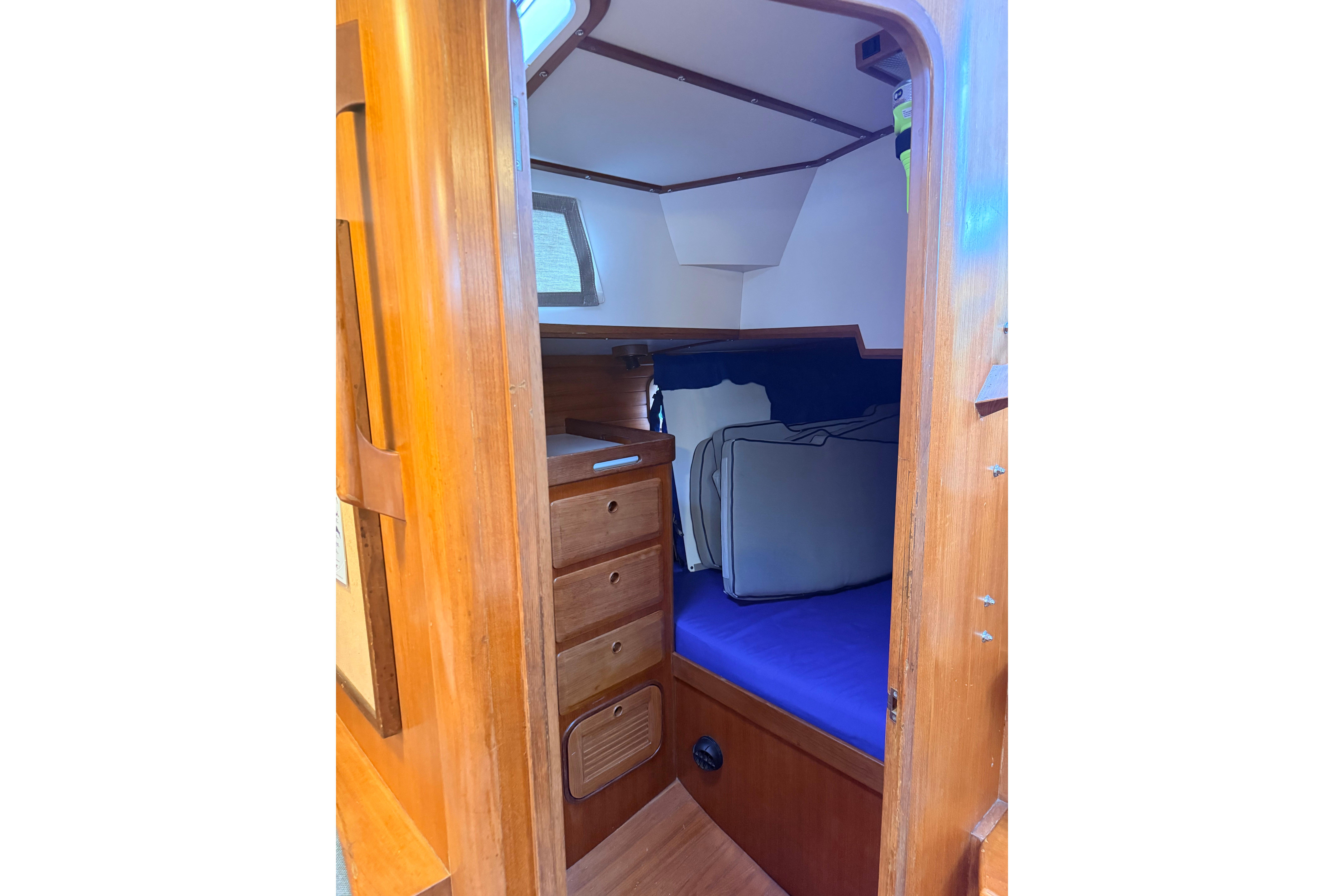 Cozy cabin interior of 1987 Norseman 400 sailboat with wooden drawers and blue bedding.