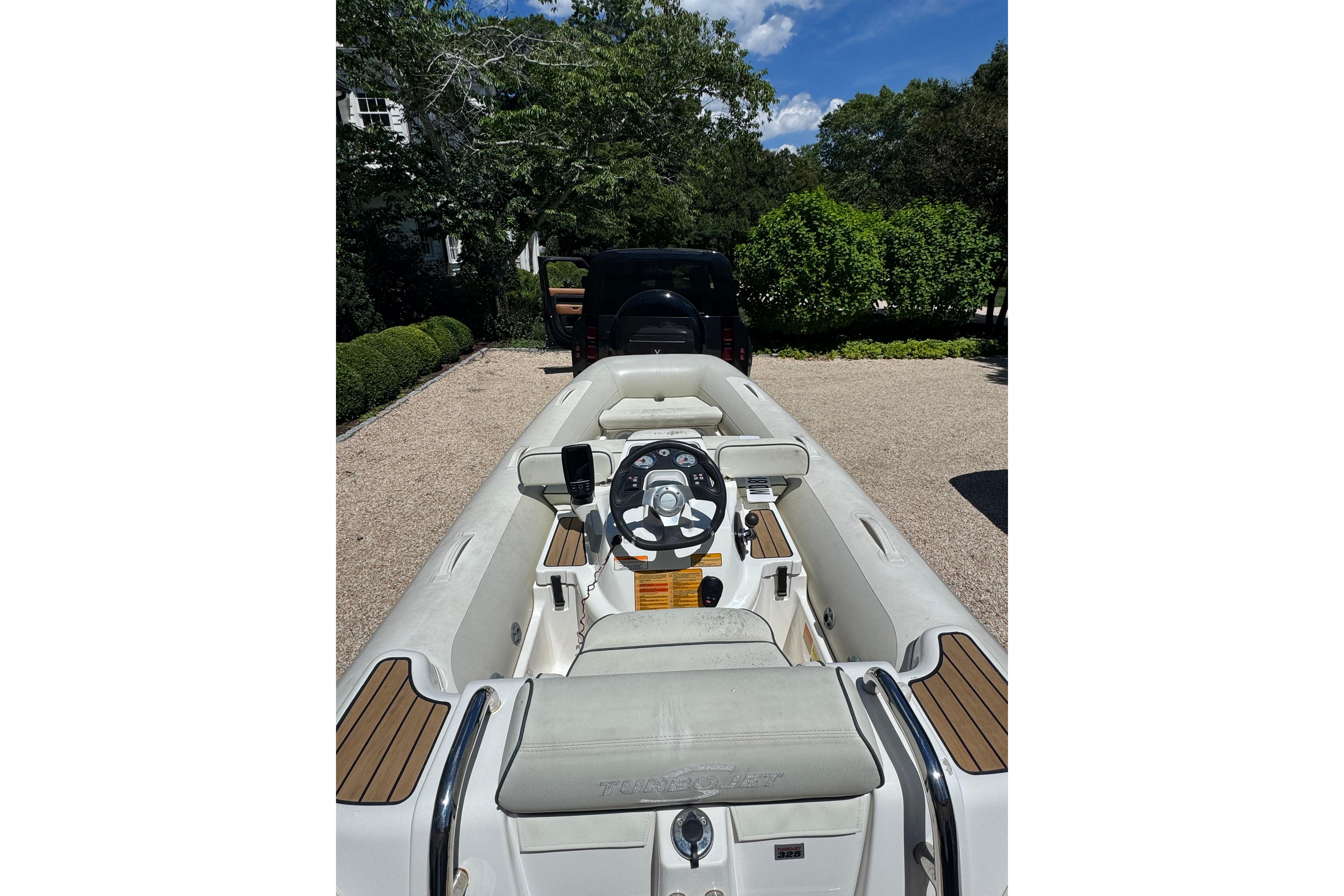 2017 Williams Jet Tenders Turbojet 325 parked on gravel driveway, surrounded by greenery.