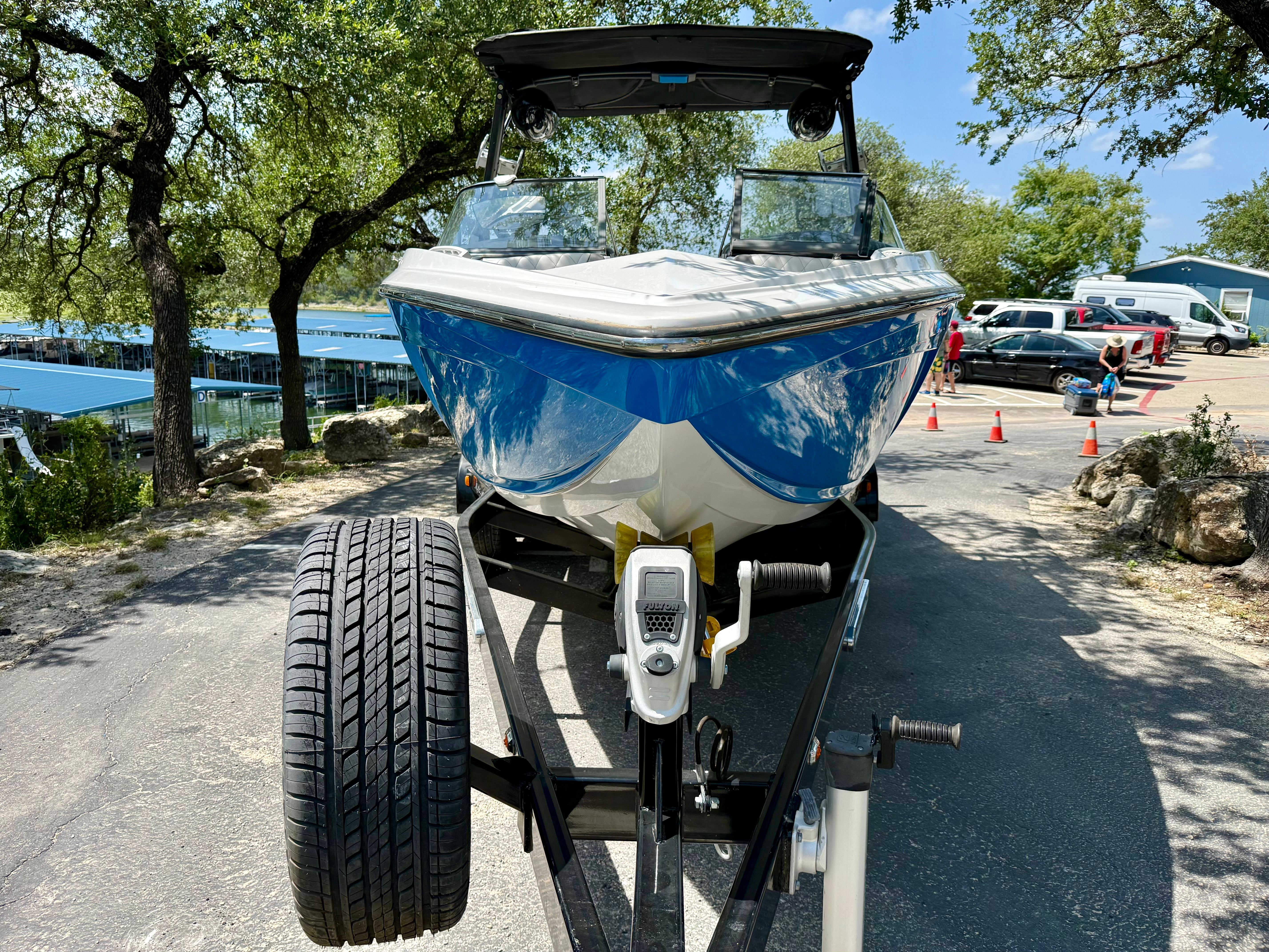 A blue and white 2017 Tigé Z3 on a trailer, surrounded by trees and cars.