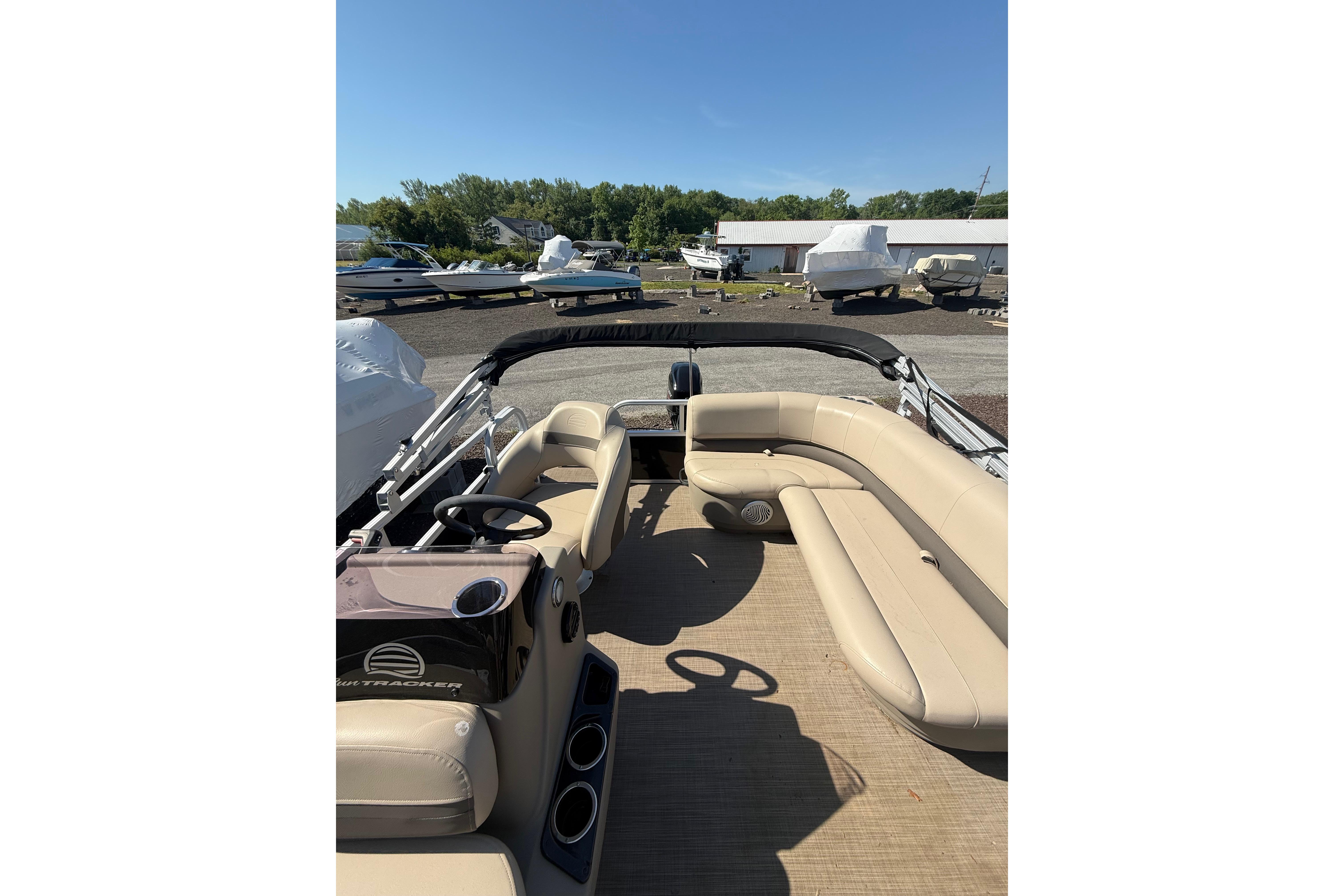 2021 Sun Tracker Bass Buggy 16 XL Select pontoon boat with beige seating and steering console.