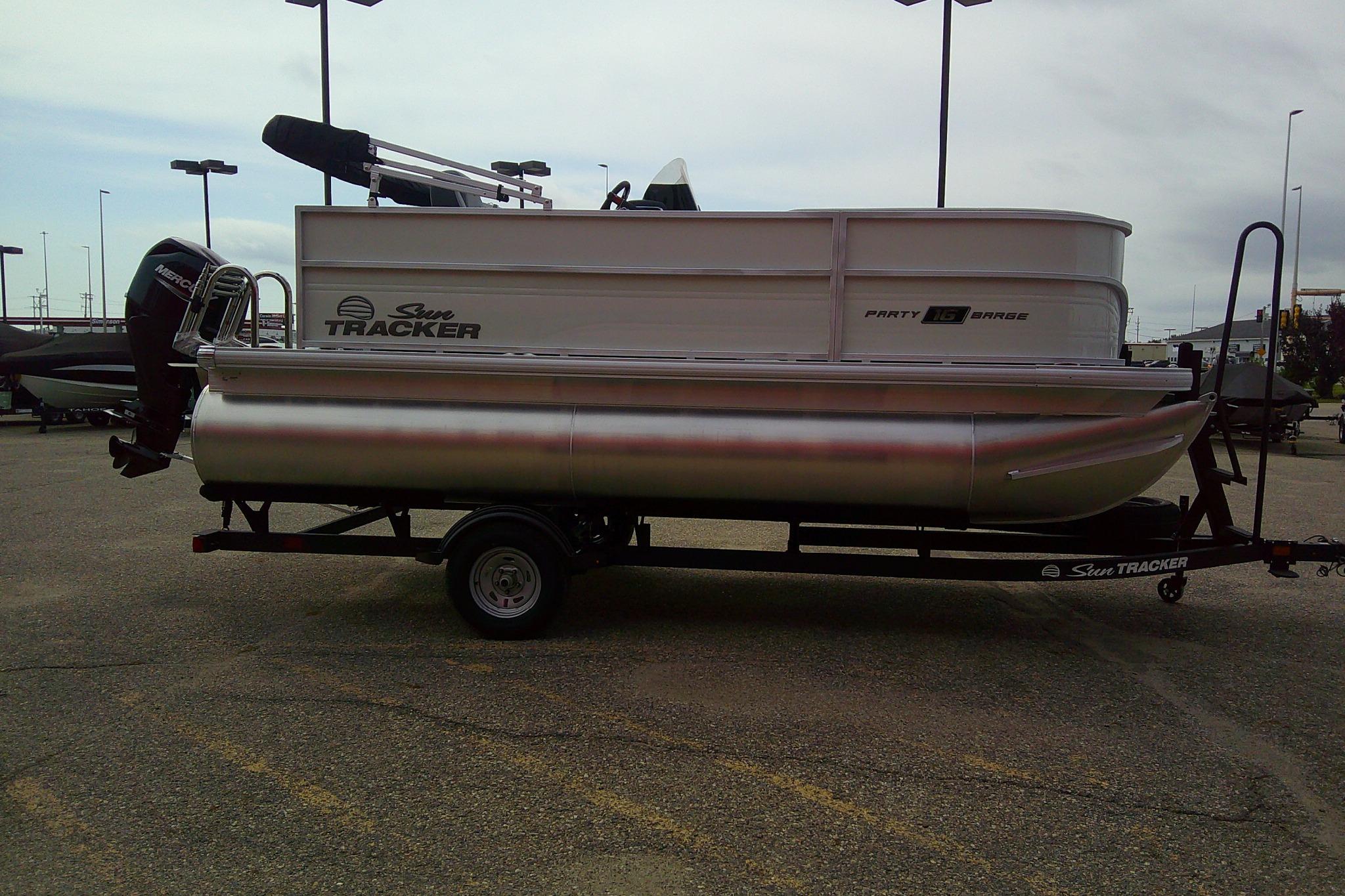 2026 Sun Tracker Party Barge 16 DLX pontoon boat on trailer in parking lot.