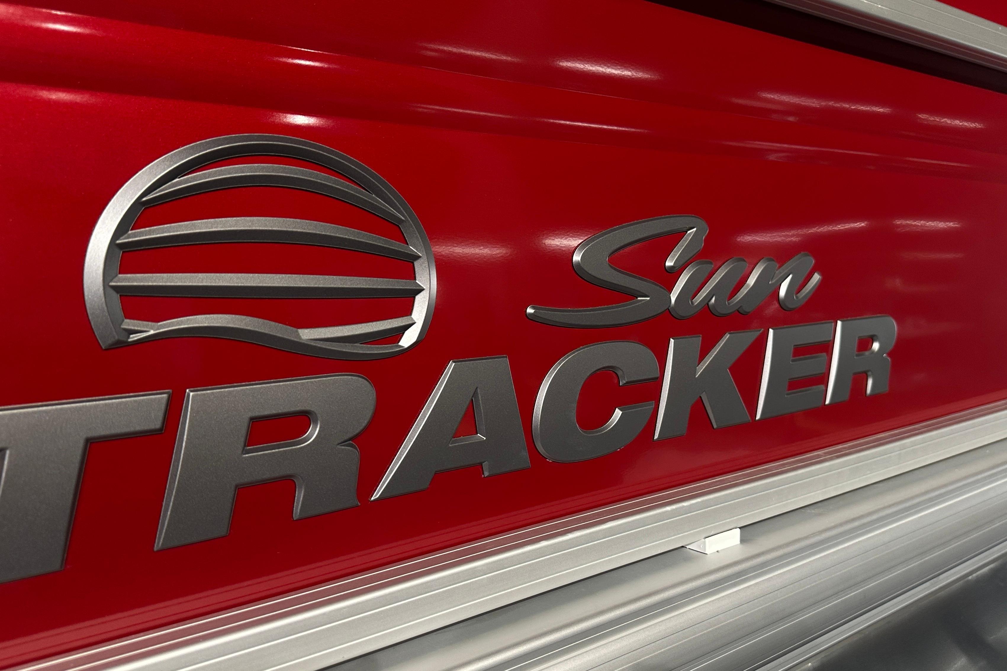 Close-up of 2026 Sun Tracker SportFish 22 DLX logo on red background.