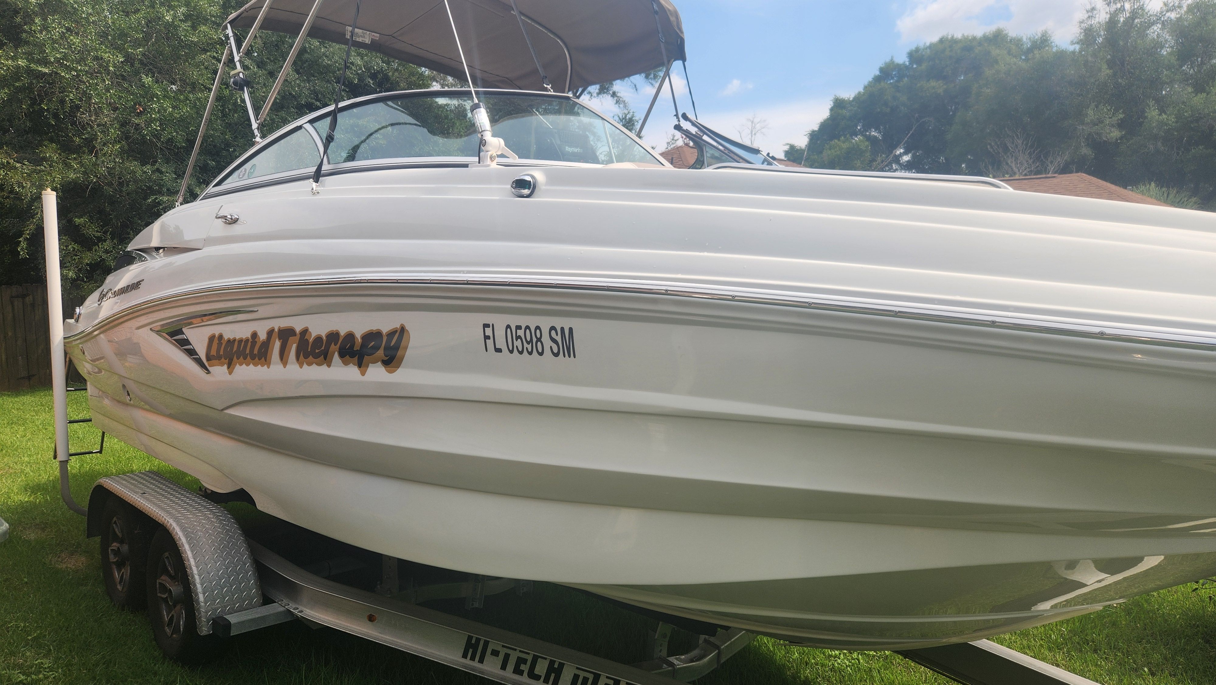 A white 2019 Crownline Eclipse E235 XS boat on a trailer, set in a grassy area.