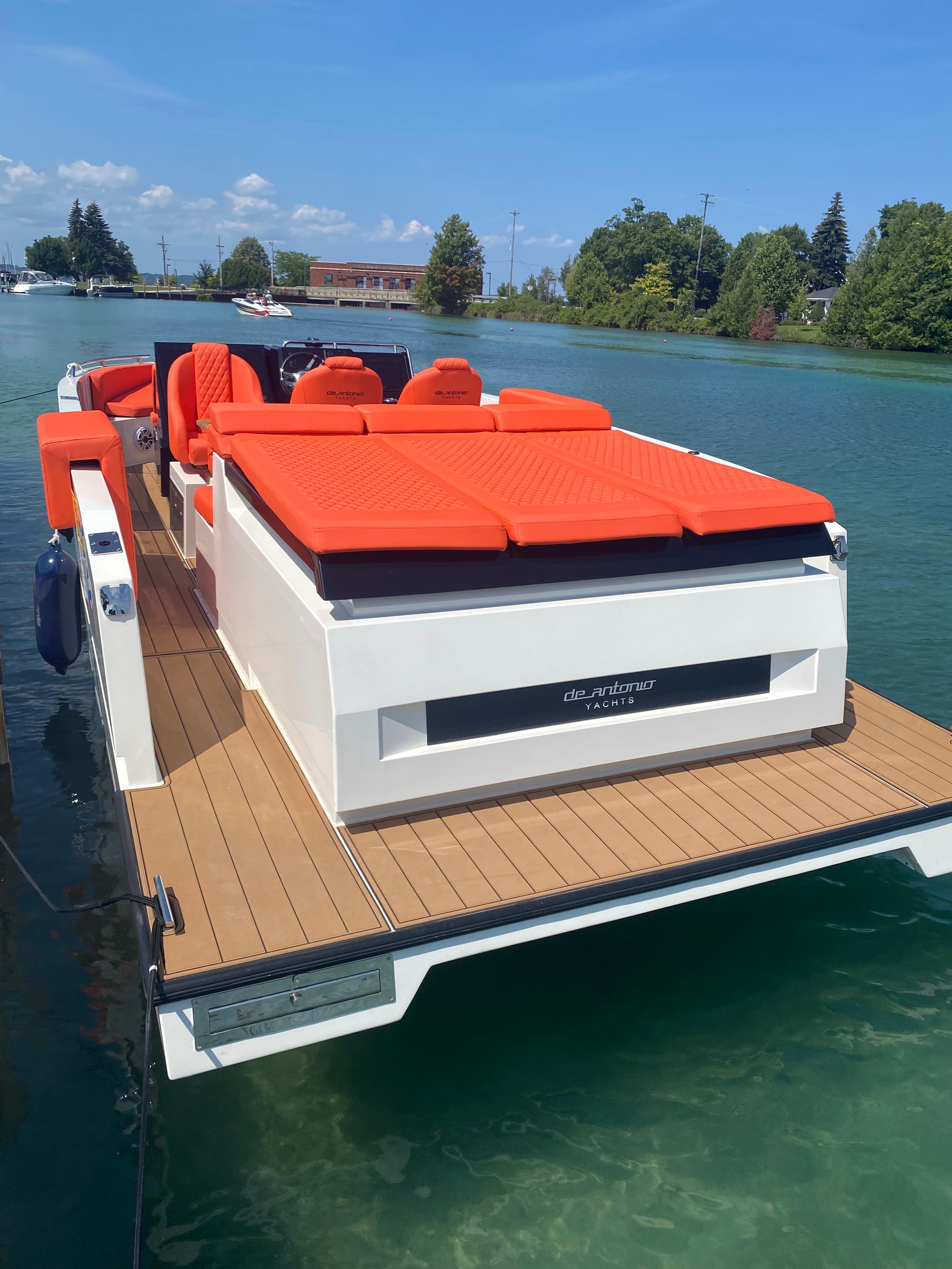 2020 De Antonio Yachts D 28 with vibrant orange seating on a serene lake.
