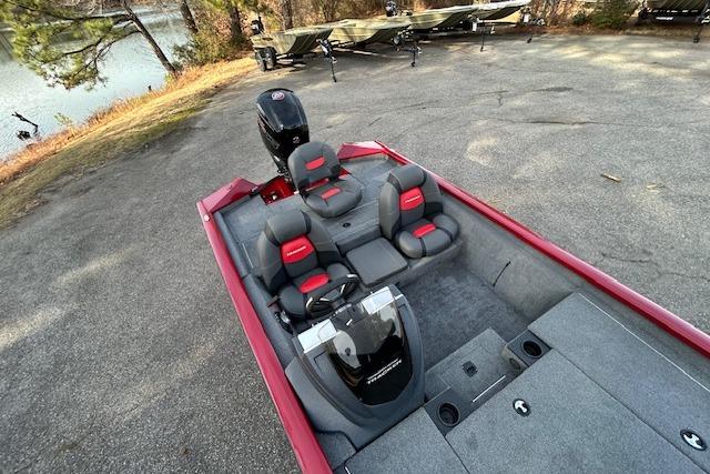 2025 Tracker Pro Team 190 boat with red and gray interior, parked near a lake.