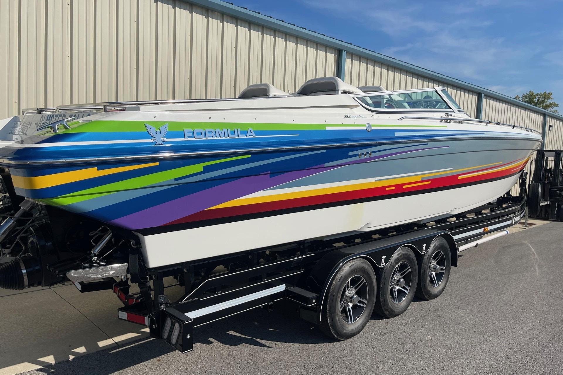 2004 Formula 382 FASTech speedboat with vibrant stripes on a triple-axle trailer.