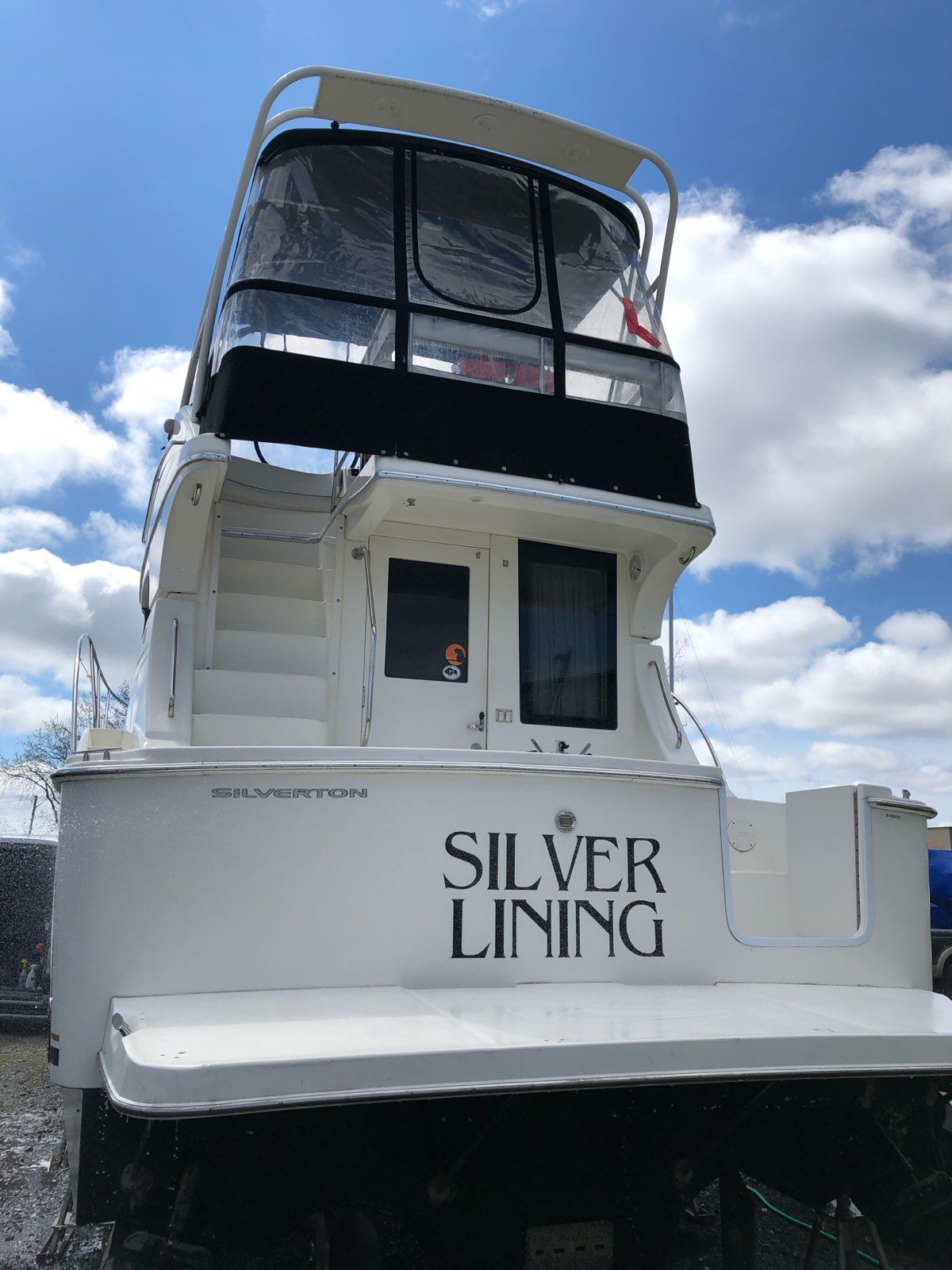 A Silverton 33 Convertible boat named "Silver Lining" is on land.