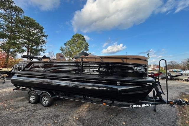 2025 Regency 230 LE3 Sport pontoon boat on trailer, parked outdoors.