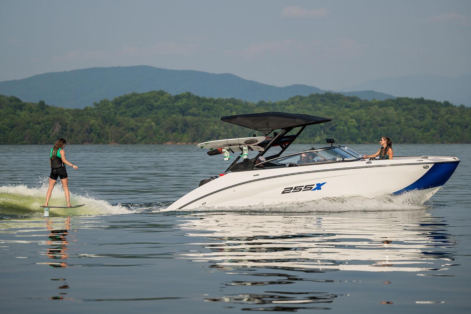 Manufacturer Provided Image: 2026 Yamaha Boats 255XE on lake with wakeboarder, surrounded by scenic mountains.