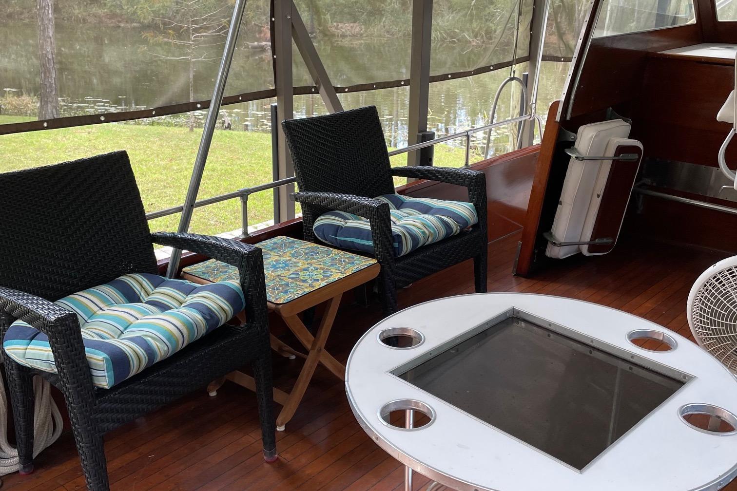 1962 Matthews 42 Double Cabin boat interior with wicker chairs and a glass table.