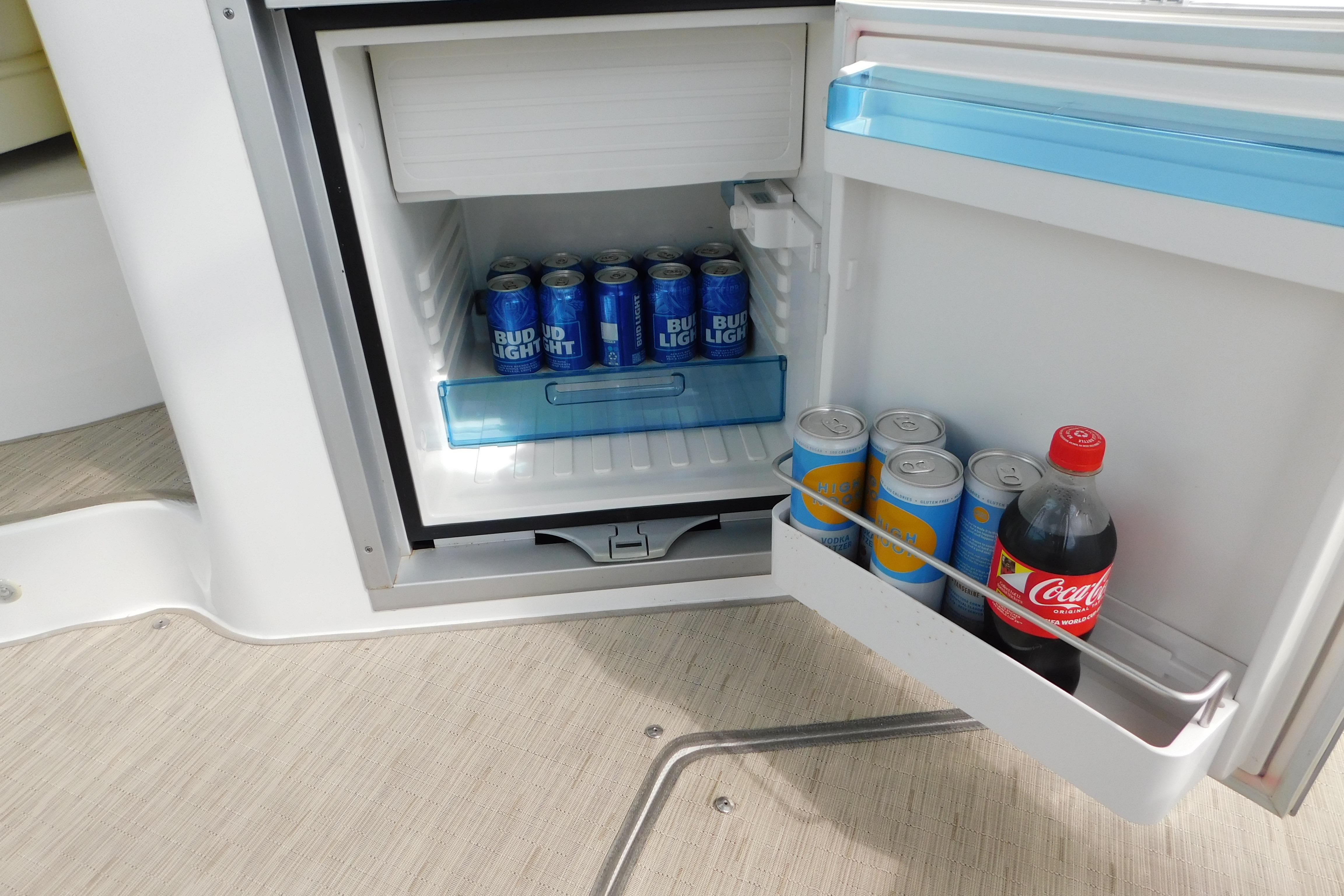 Mini fridge on 2017 Rinker EX 320 boat stocked with beverages, including Bud Light and Coca-Cola.