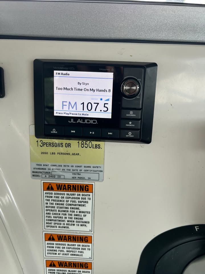 JL Audio radio on Vectra 2402 IO boat, FM 107.5, safety warnings.