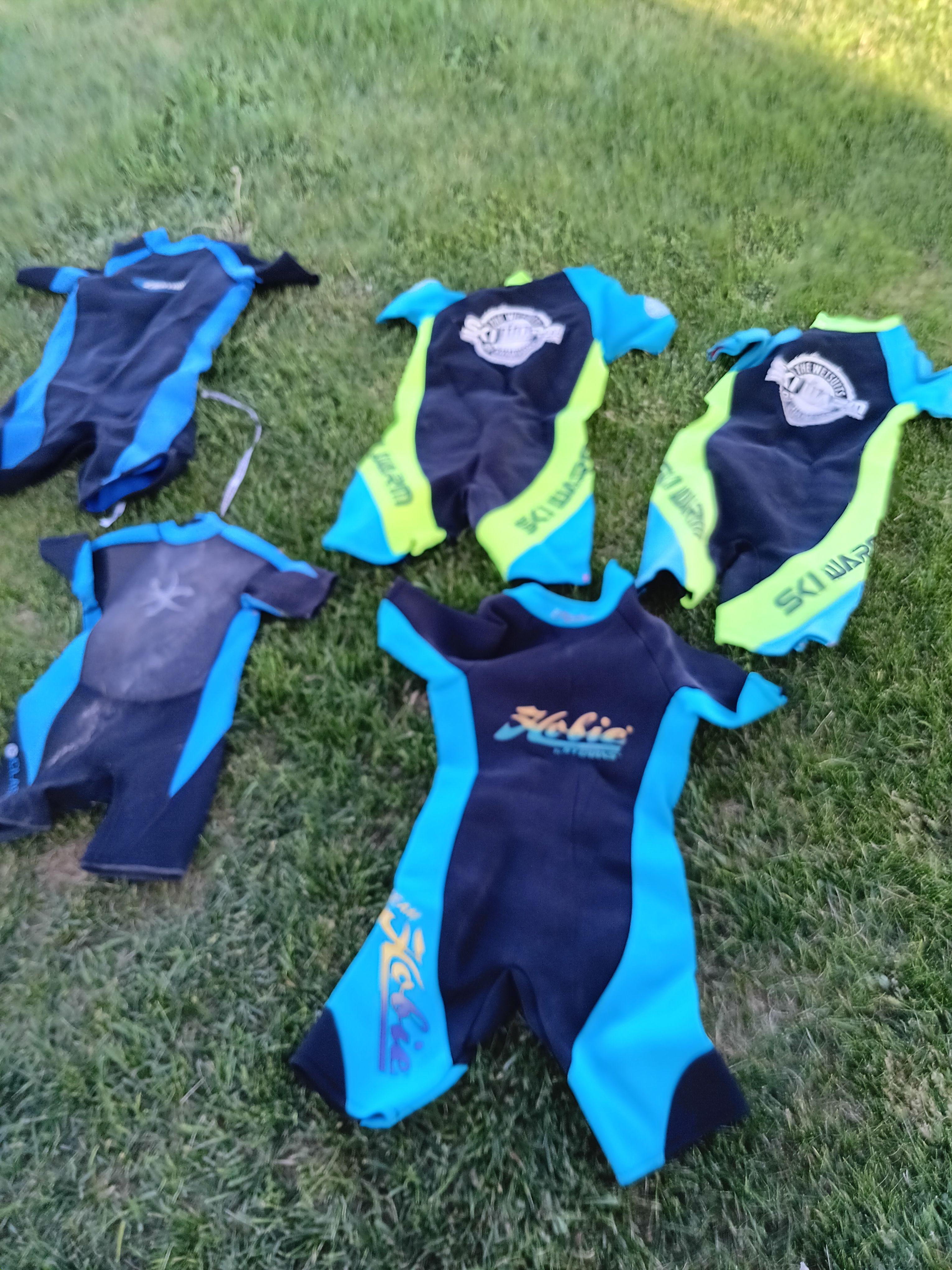 Five colorful wetsuits on green grass, Malibu Skier 1991.