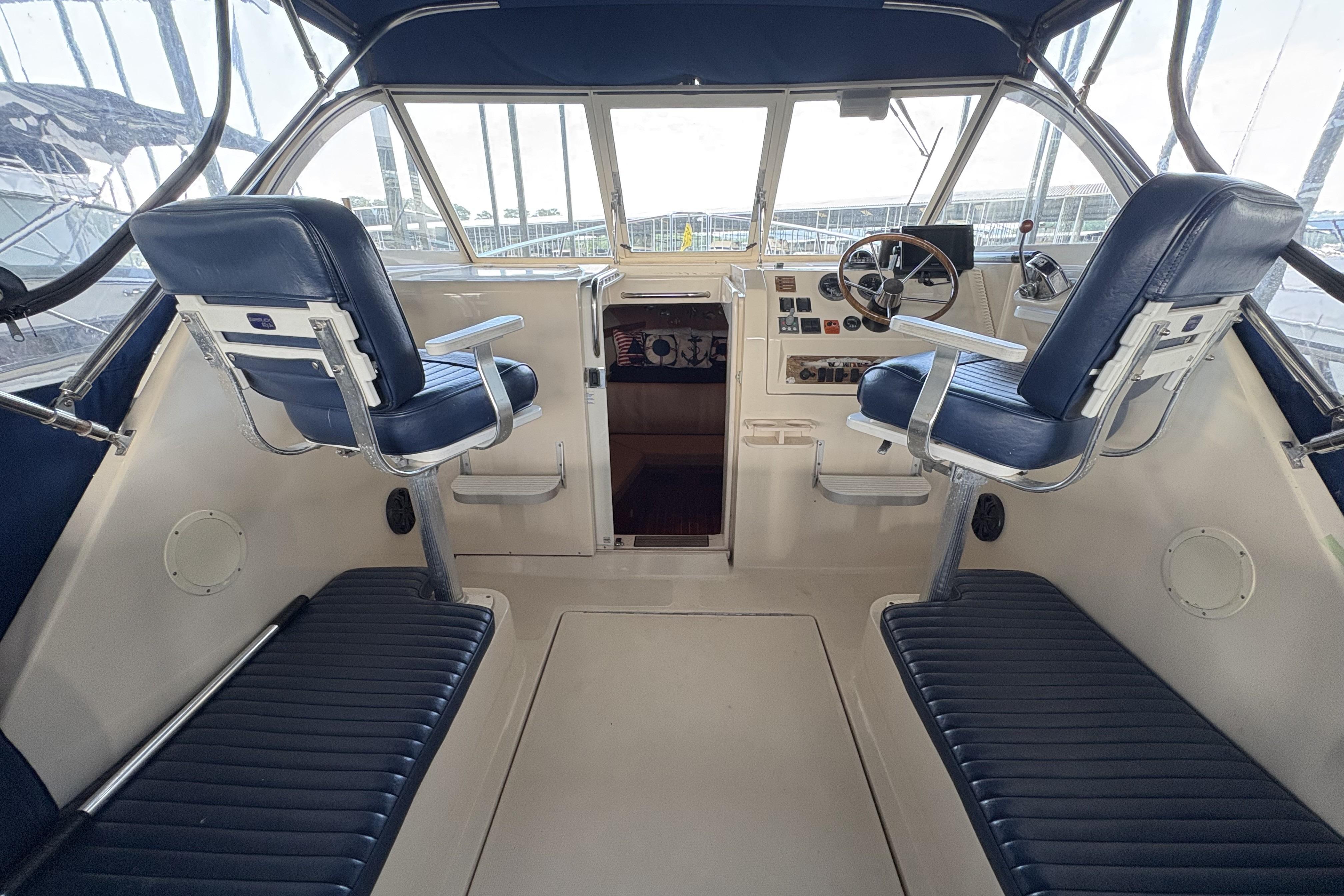 2003 Mainship Pilot 30-II cockpit with blue seating and steering wheel, showcasing nautical design.