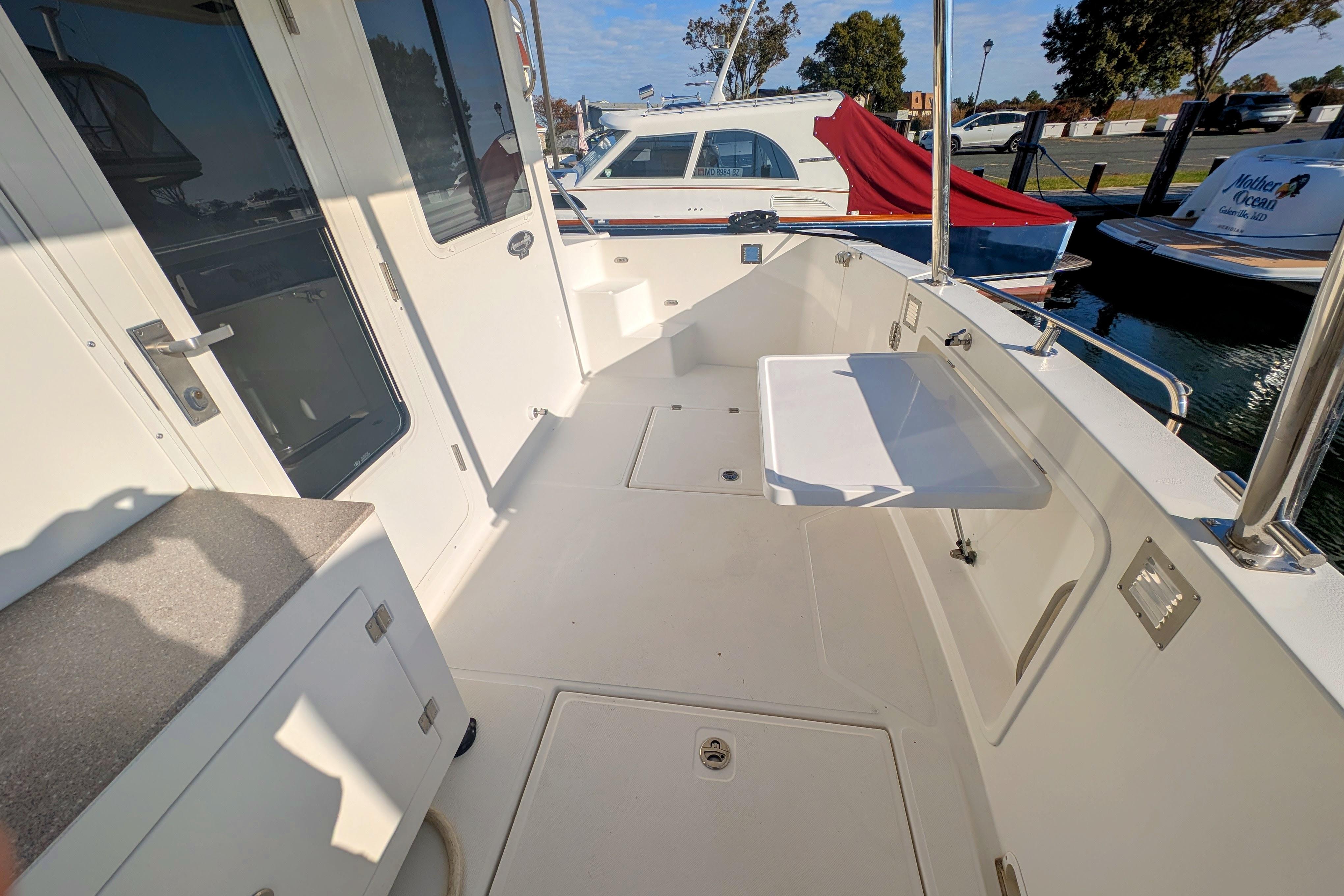 2015 American Tug 435 boat deck with seating and storage, docked at marina.