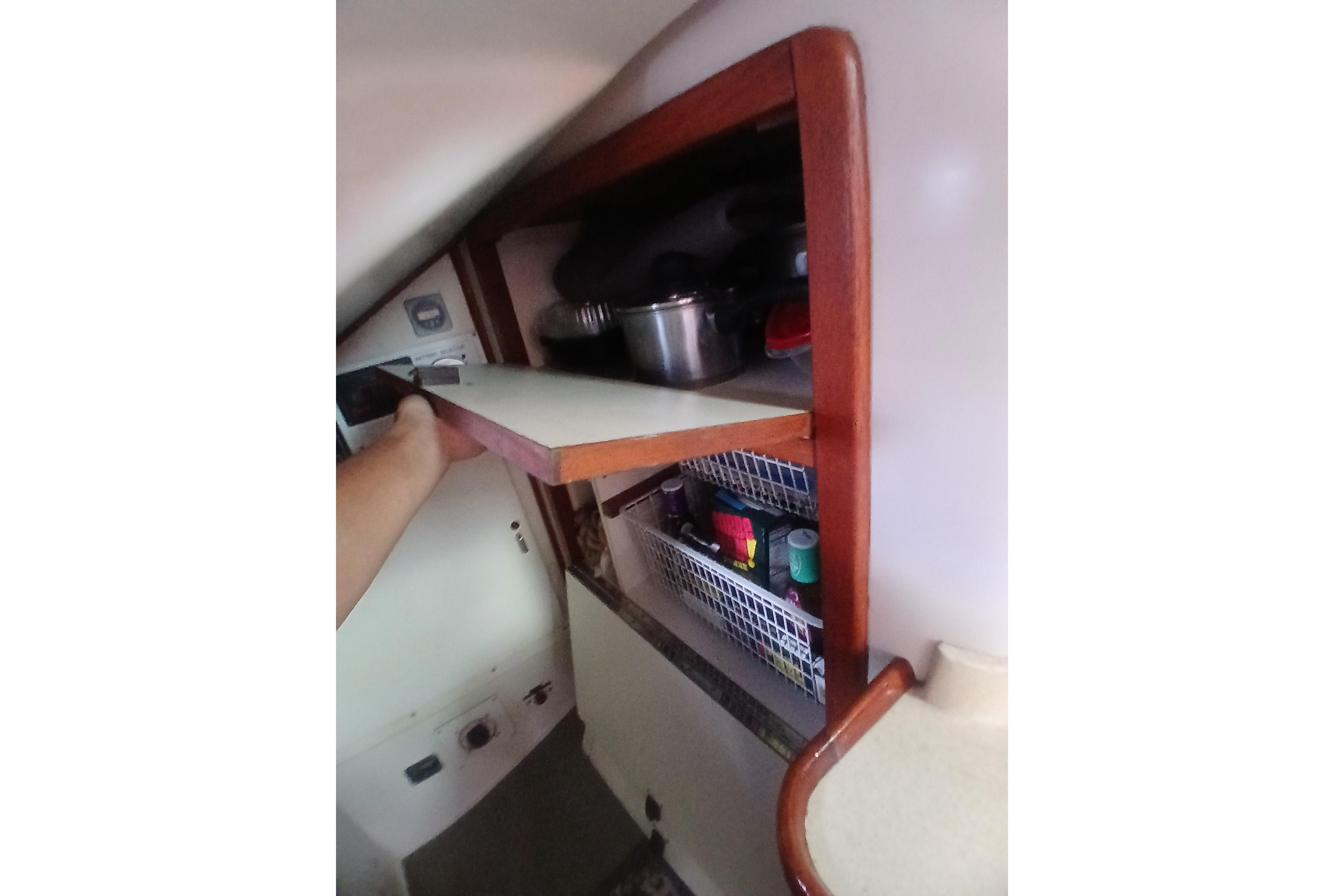 Interior storage of 1995 Catalina 42 MkII sailboat with wooden shelves and kitchen items.
