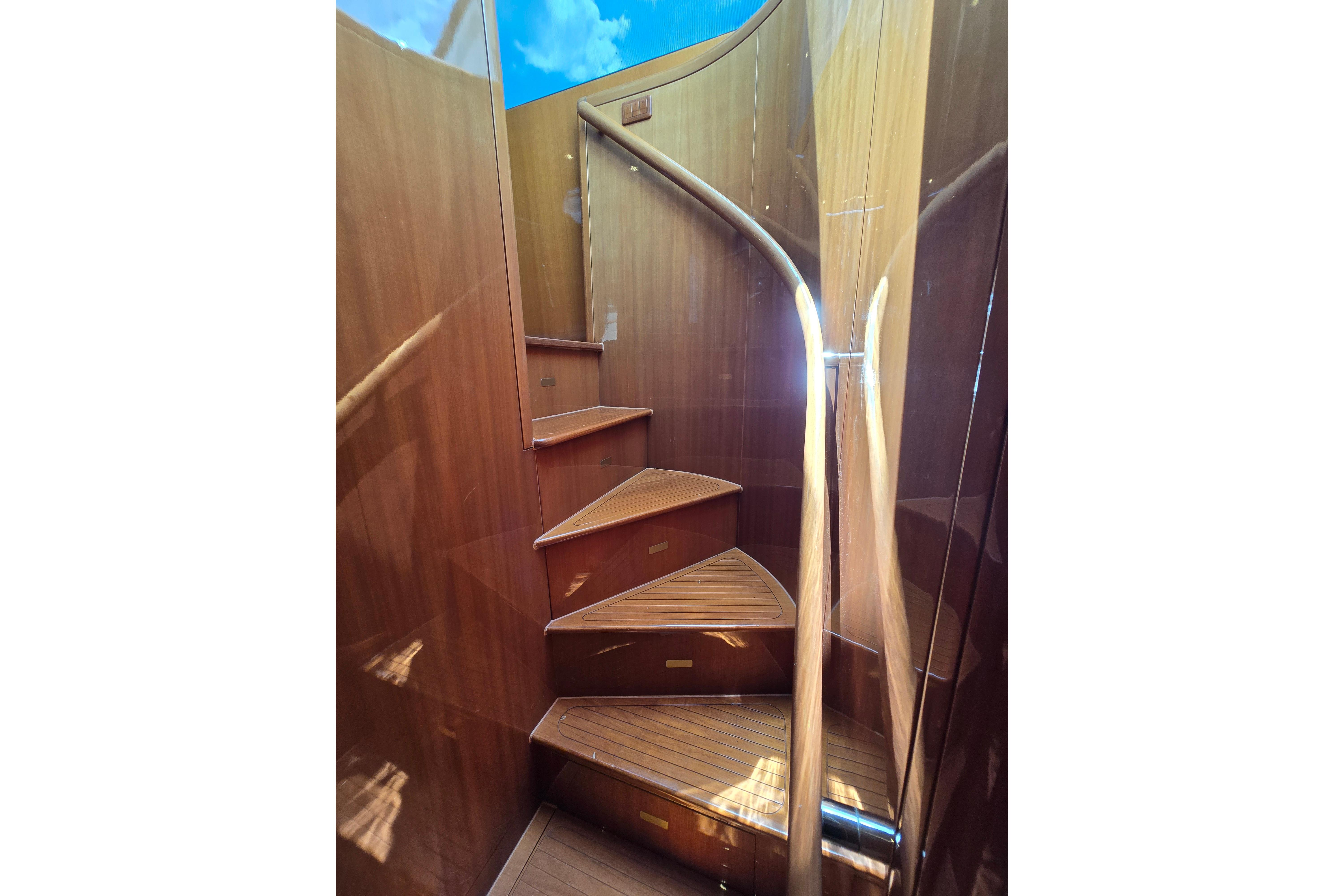 Wooden spiral staircase inside 2004 Grand Harbour 58 yacht, showcasing elegant craftsmanship.