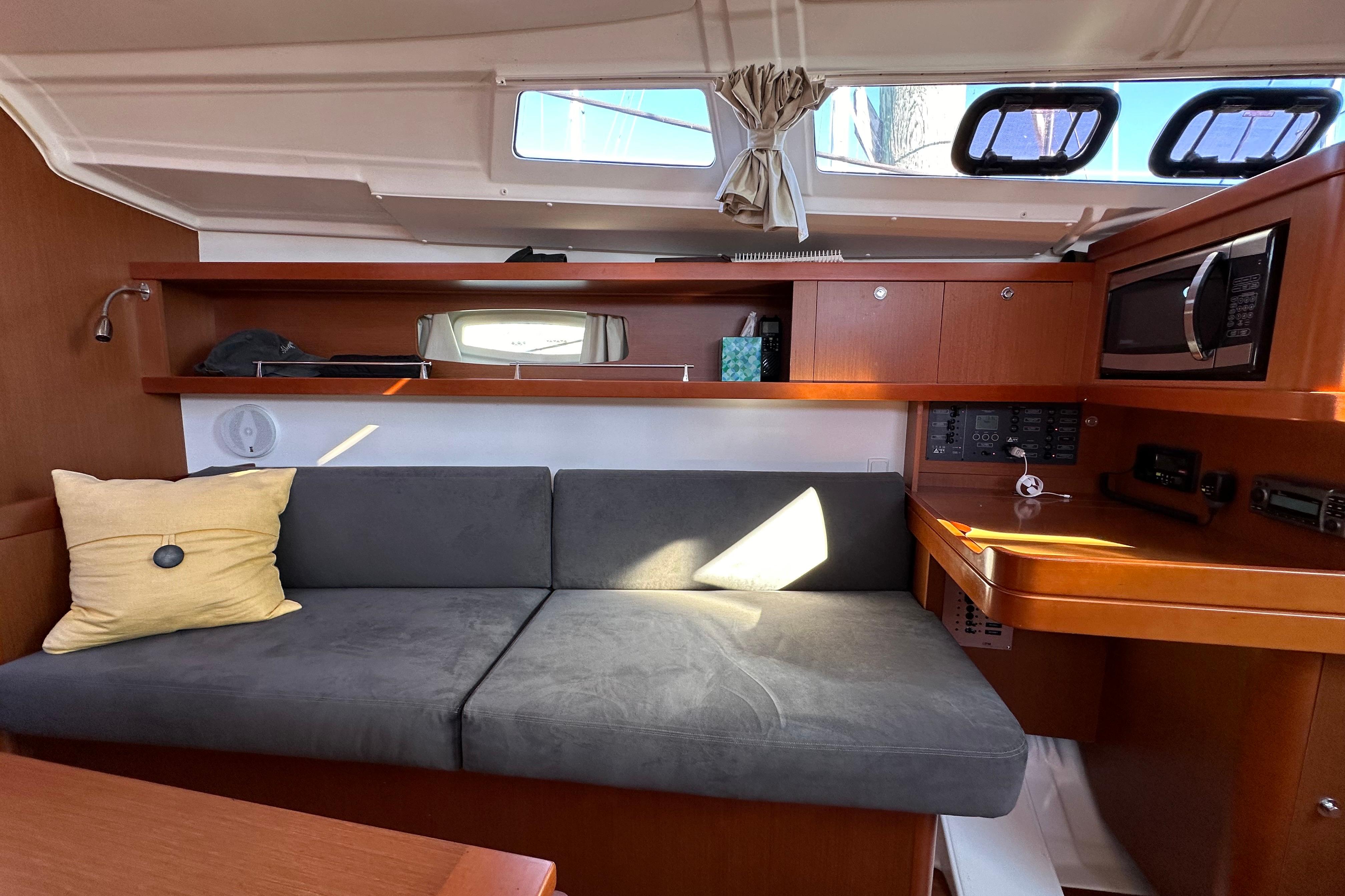 Interior of 2015 Beneteau Oceanis 37 yacht with sofa, wooden cabinetry, and modern amenities.