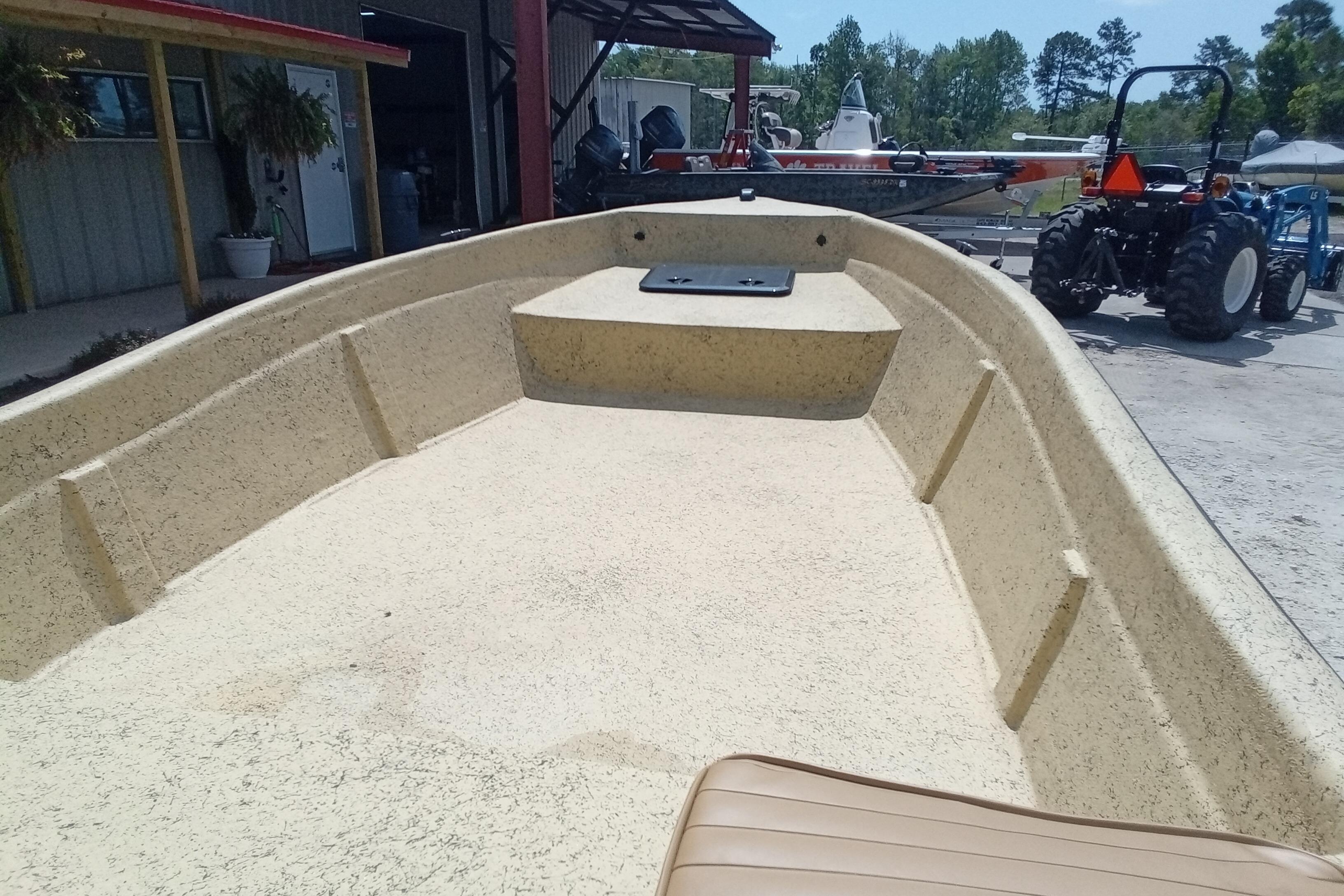 Open deck of a 2025 Fibercraft F16 boat, parked near a workshop.
