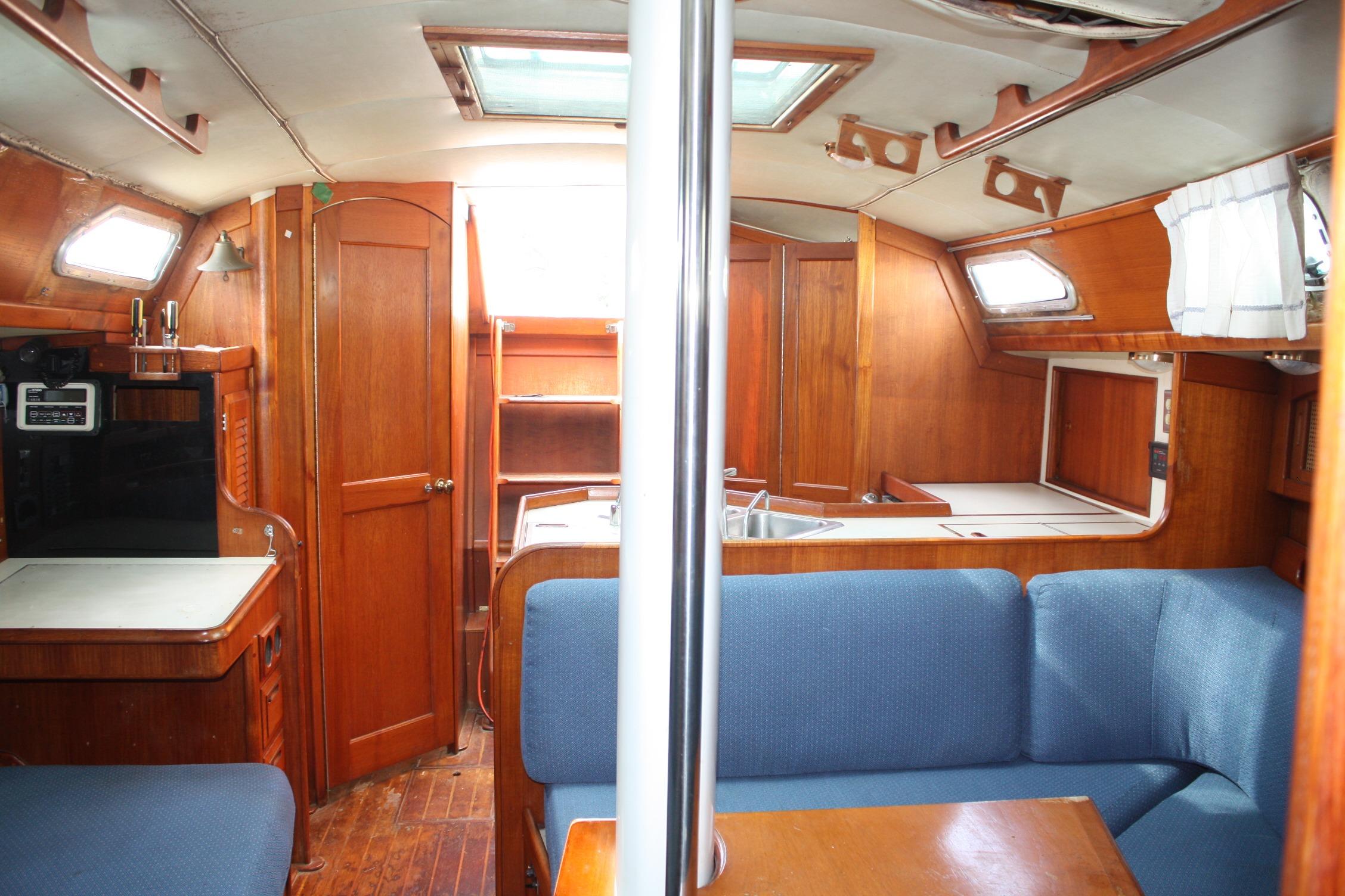 Interior of a 1987 Ericson 38-200 sailboat with wooden cabinetry and blue seating.