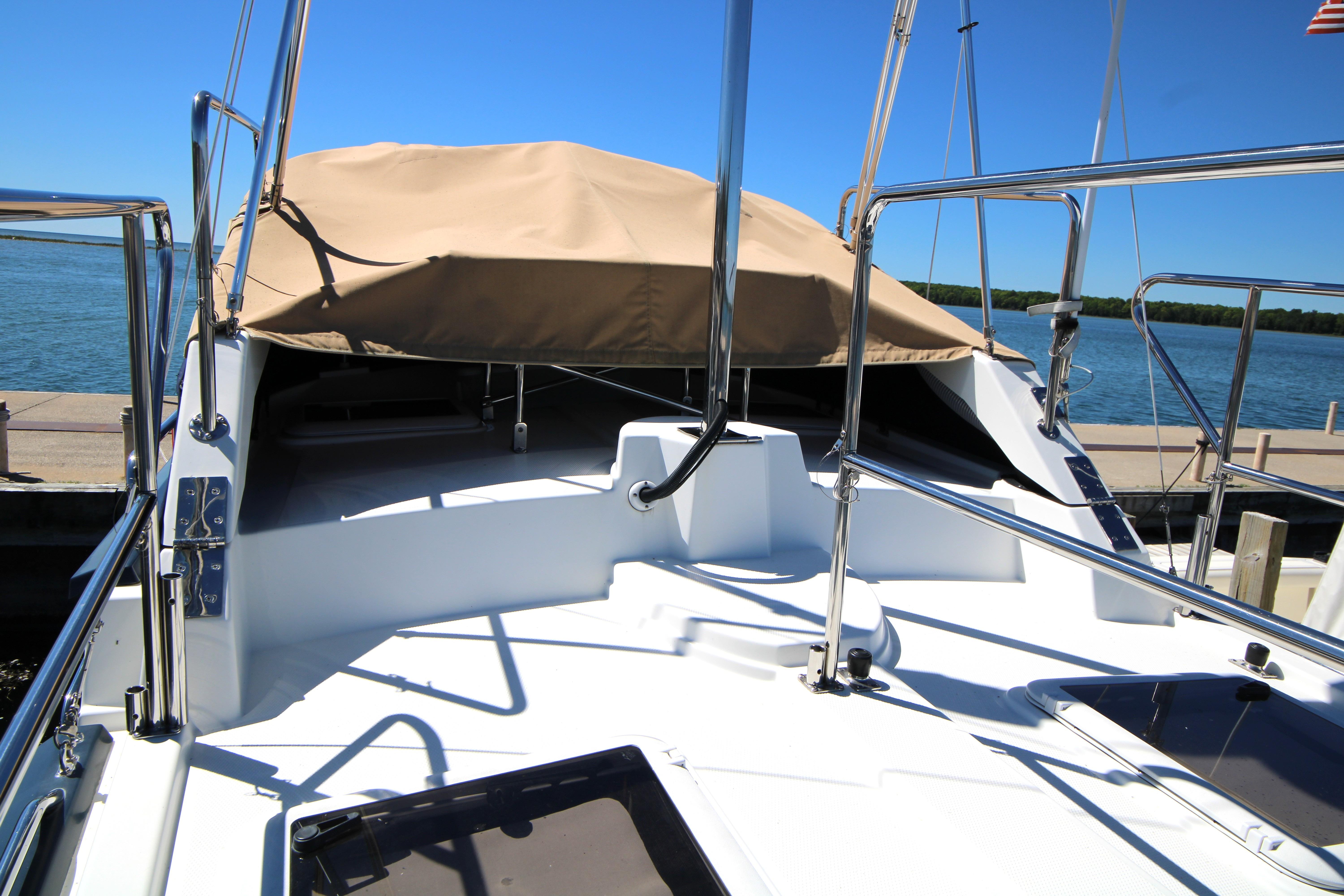 2013 Ranger Tugs R-31 CB boat deck with tan cover, docked by the water.