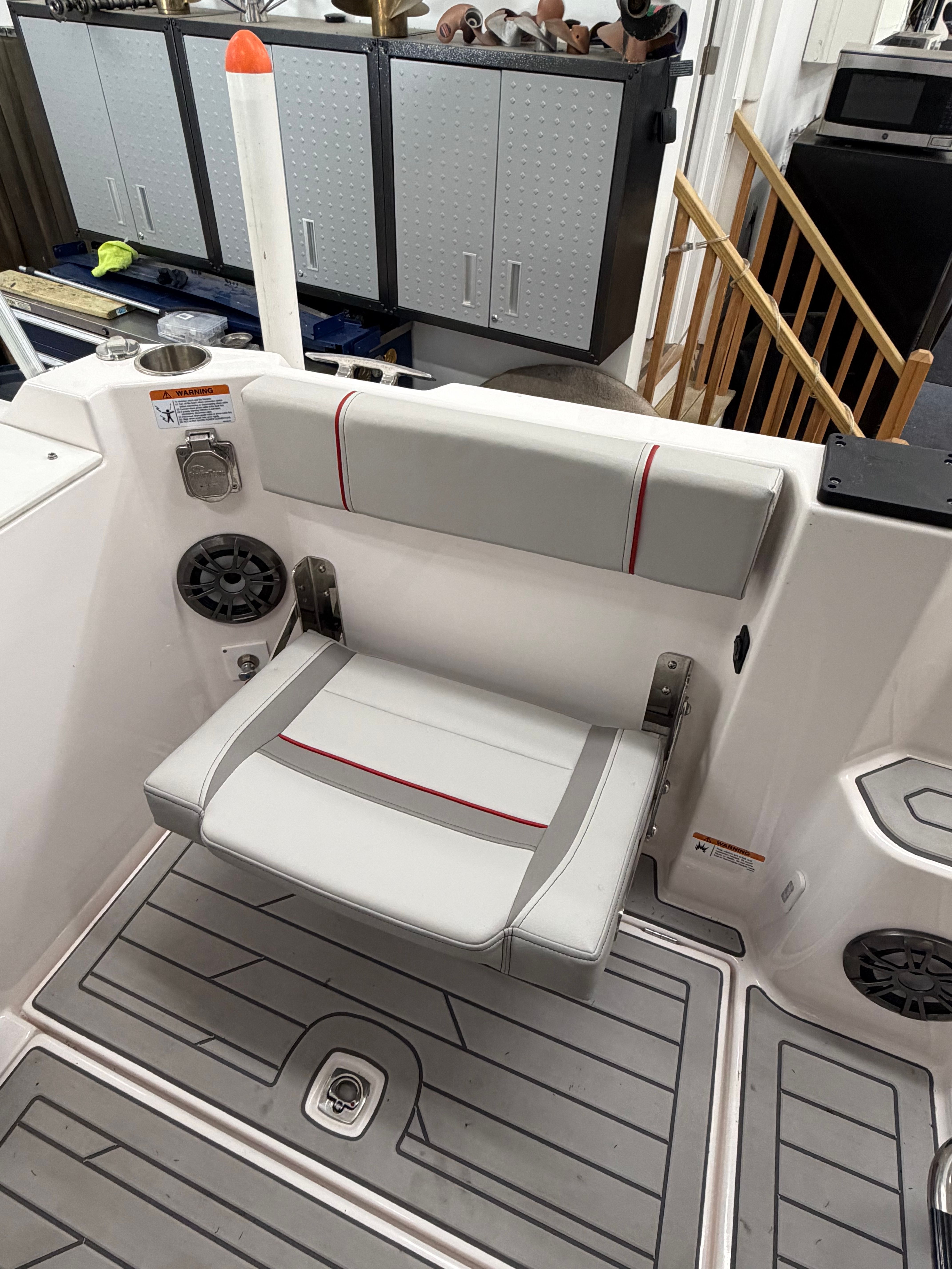 A seating area on a boat with gray and red accents, surrounded by speakers.