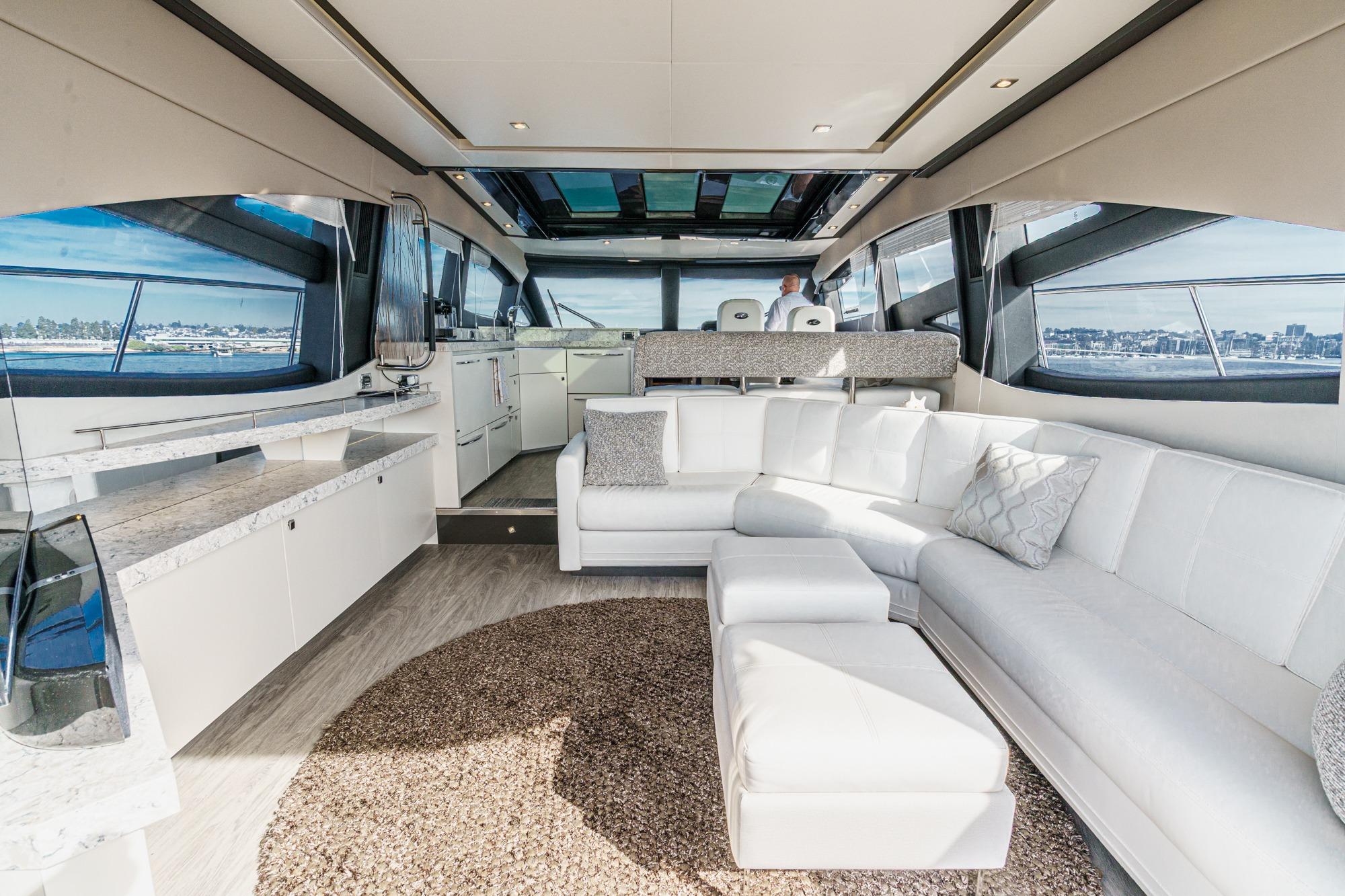 Luxurious interior of 2016 Sea Ray L590 yacht with white seating and panoramic windows.
