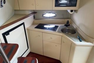 2002 Cruisers Yachts 3372 Express cabin kitchen with stove, sink, and storage cabinets.