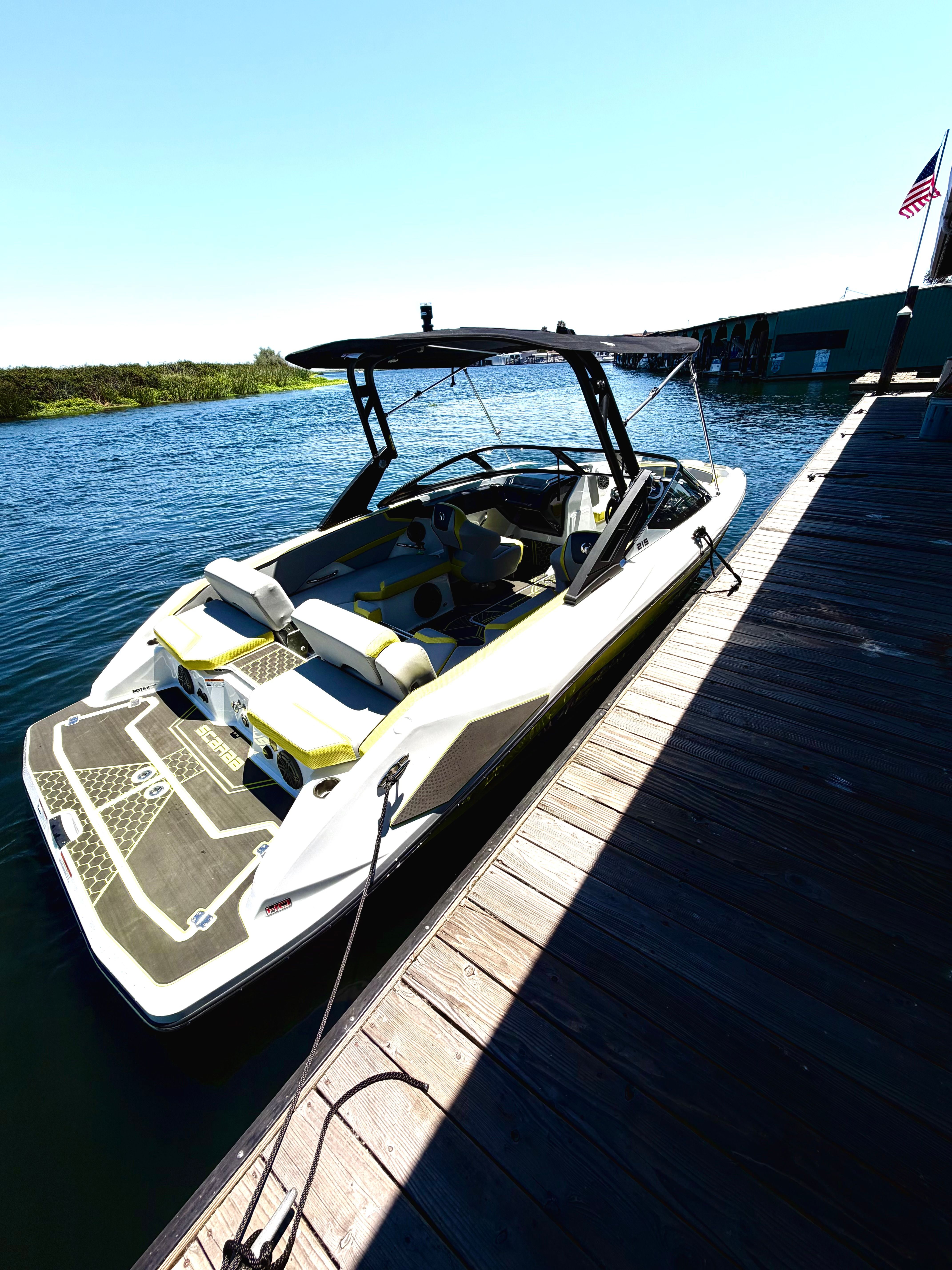 A 2023 Scarab 215 ID boat docked in sunny weather. It features a sleek, modern design.