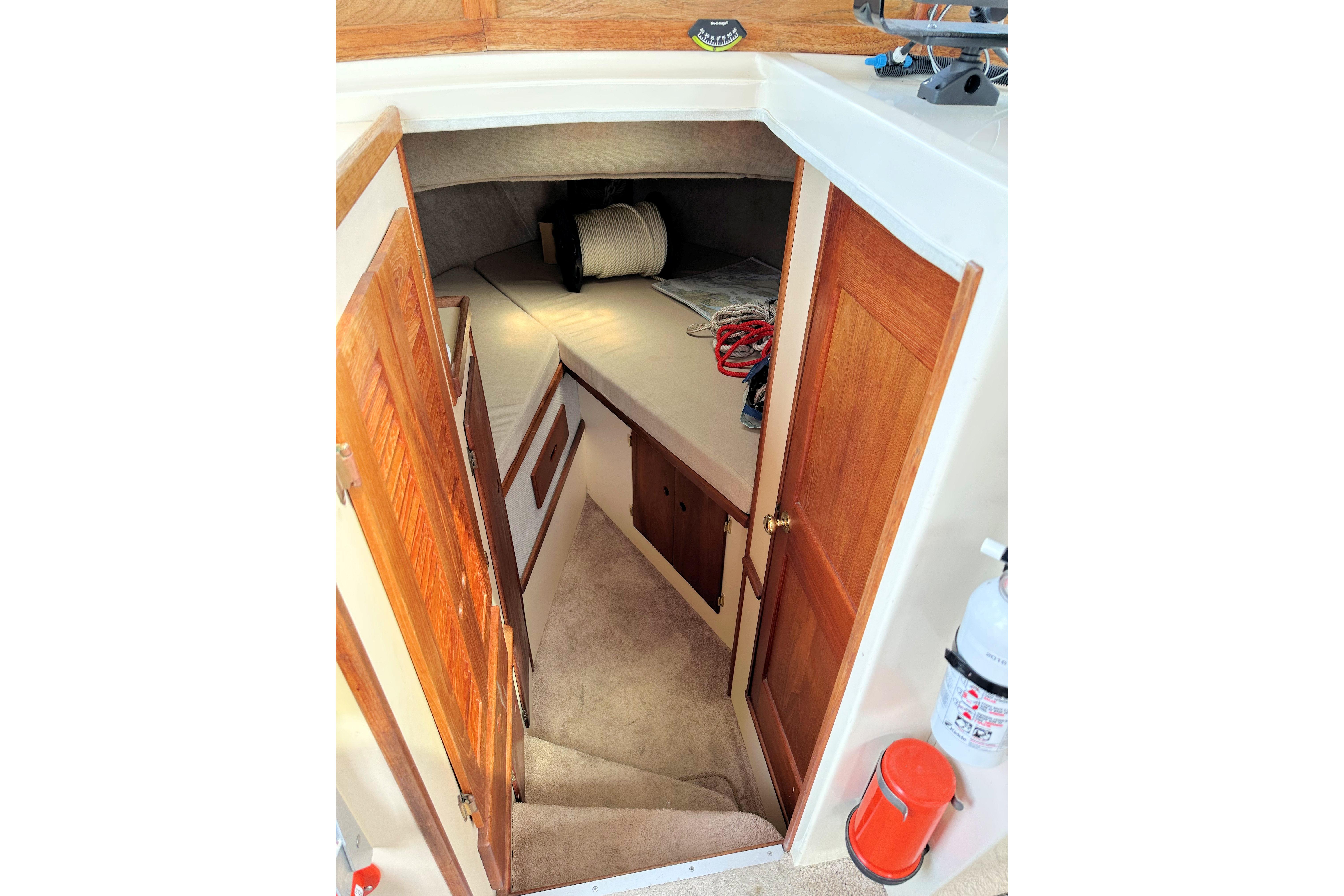 Interior cabin view of a 1985 Nordic Tug 26, featuring wooden doors and cozy sleeping area.