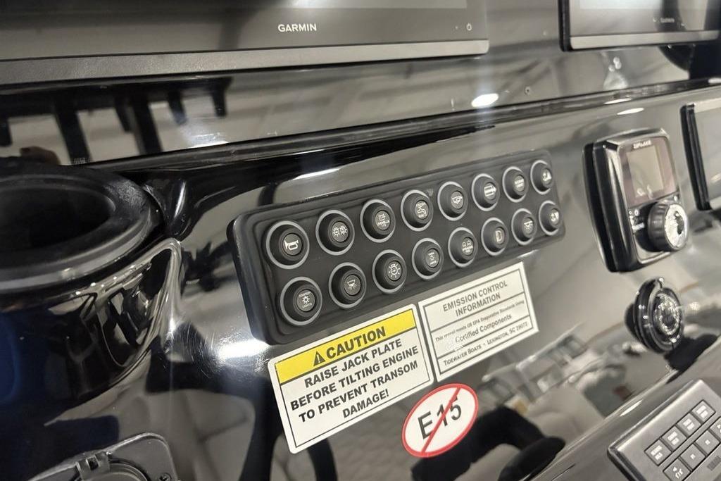 Control panel of 2026 Tidewater 3100 Carolina Bay boat with various buttons and warning labels.