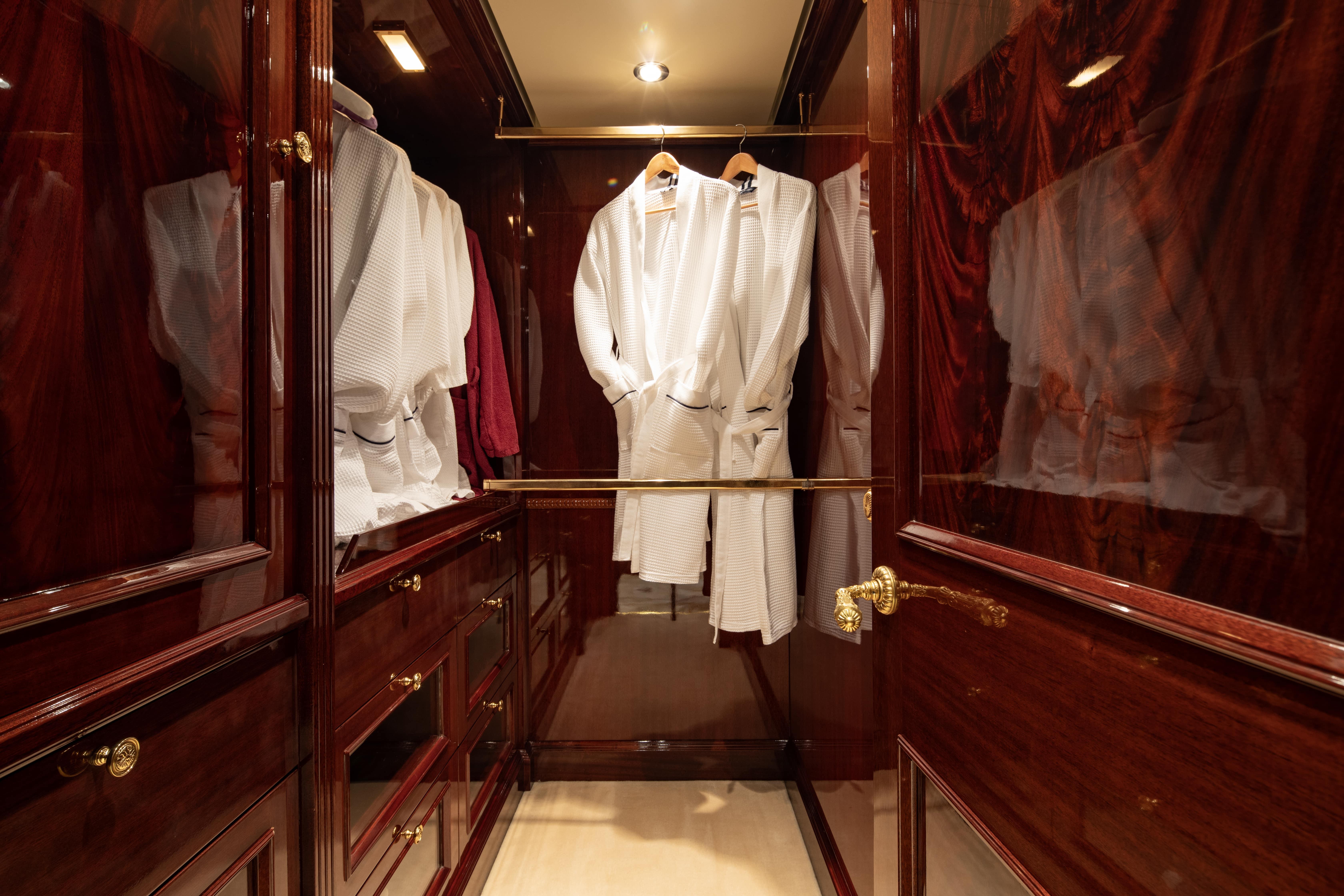 Luxurious yacht closet with wooden finish and hanging white robes, CRN 185, 2008 model.
