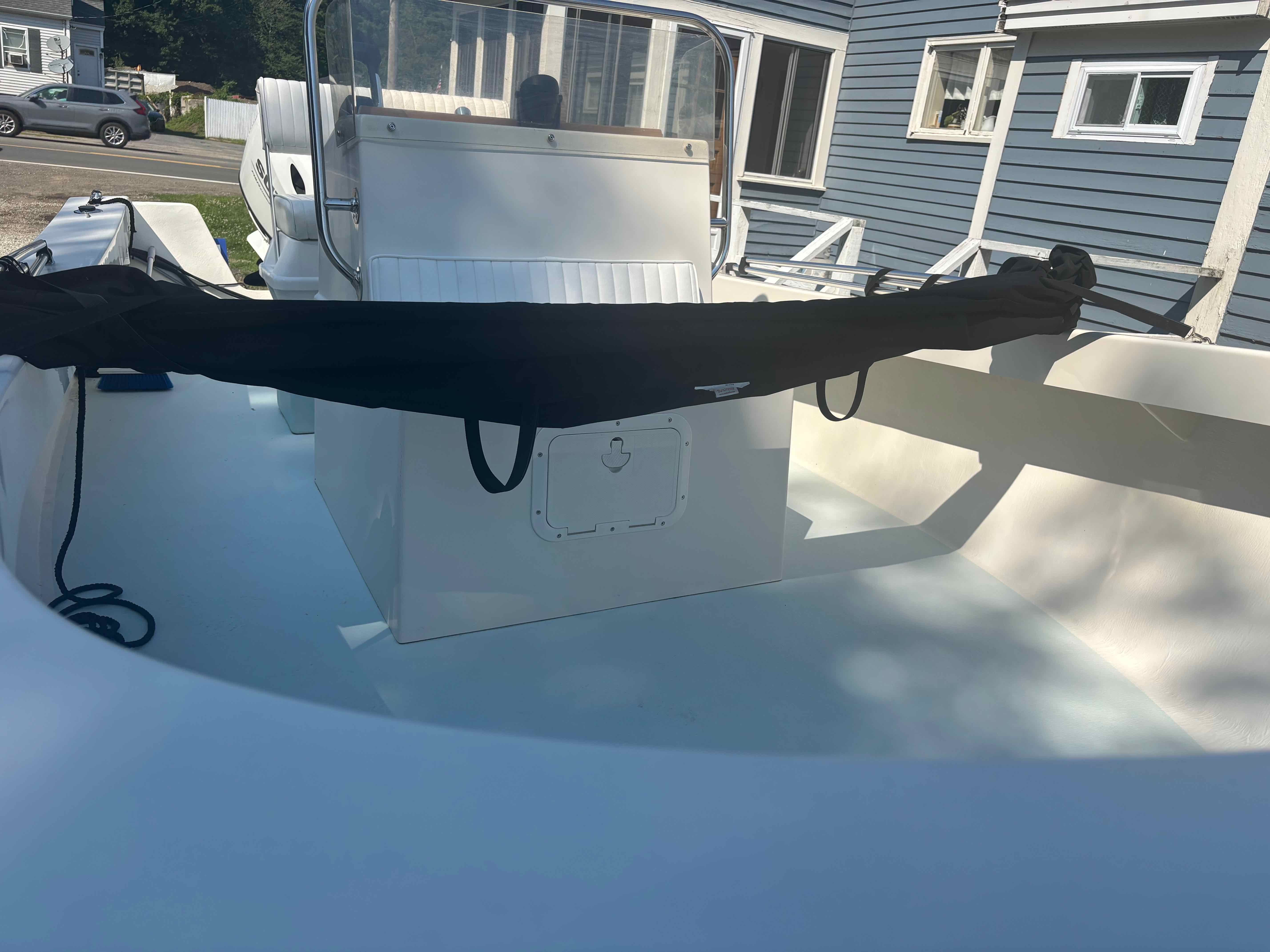 A 2016 Surfside 21 Center Console boat with a white deck and black cover.
