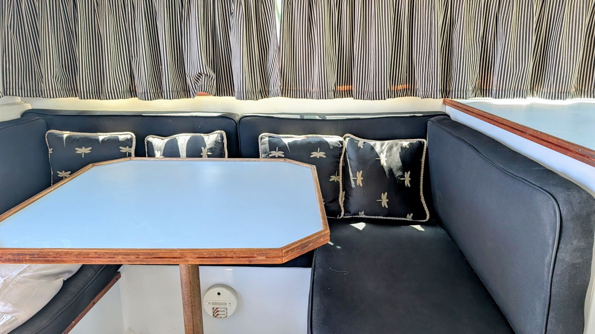 Interior of the 1987 Chris-Craft 320 Amerosport Express with blue cushions and striped curtains.